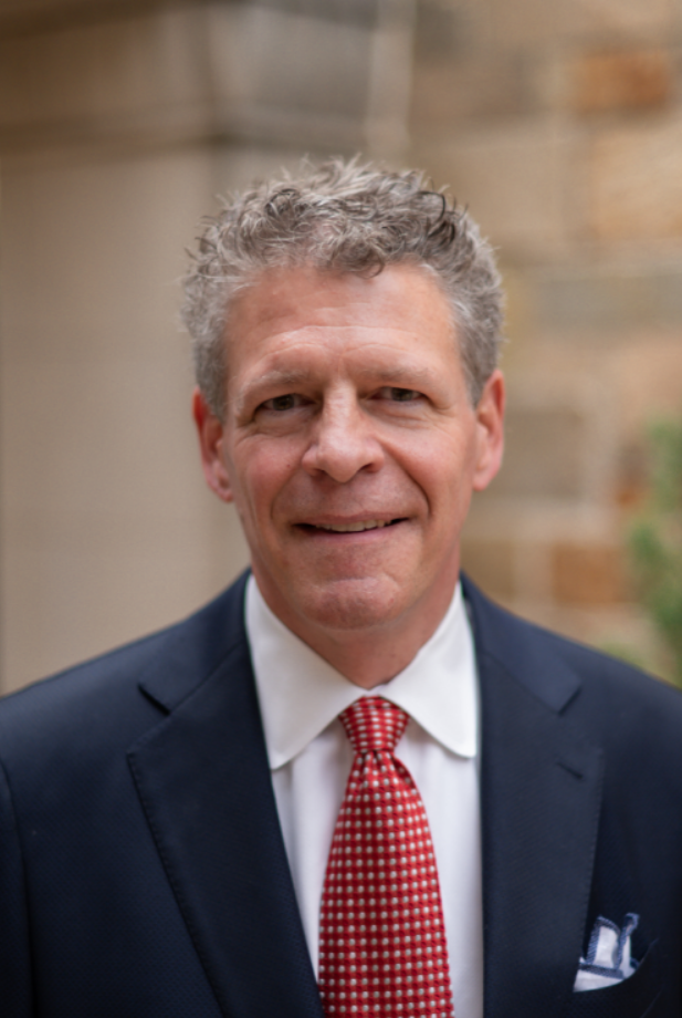 A man wearing a dark suit and red tie