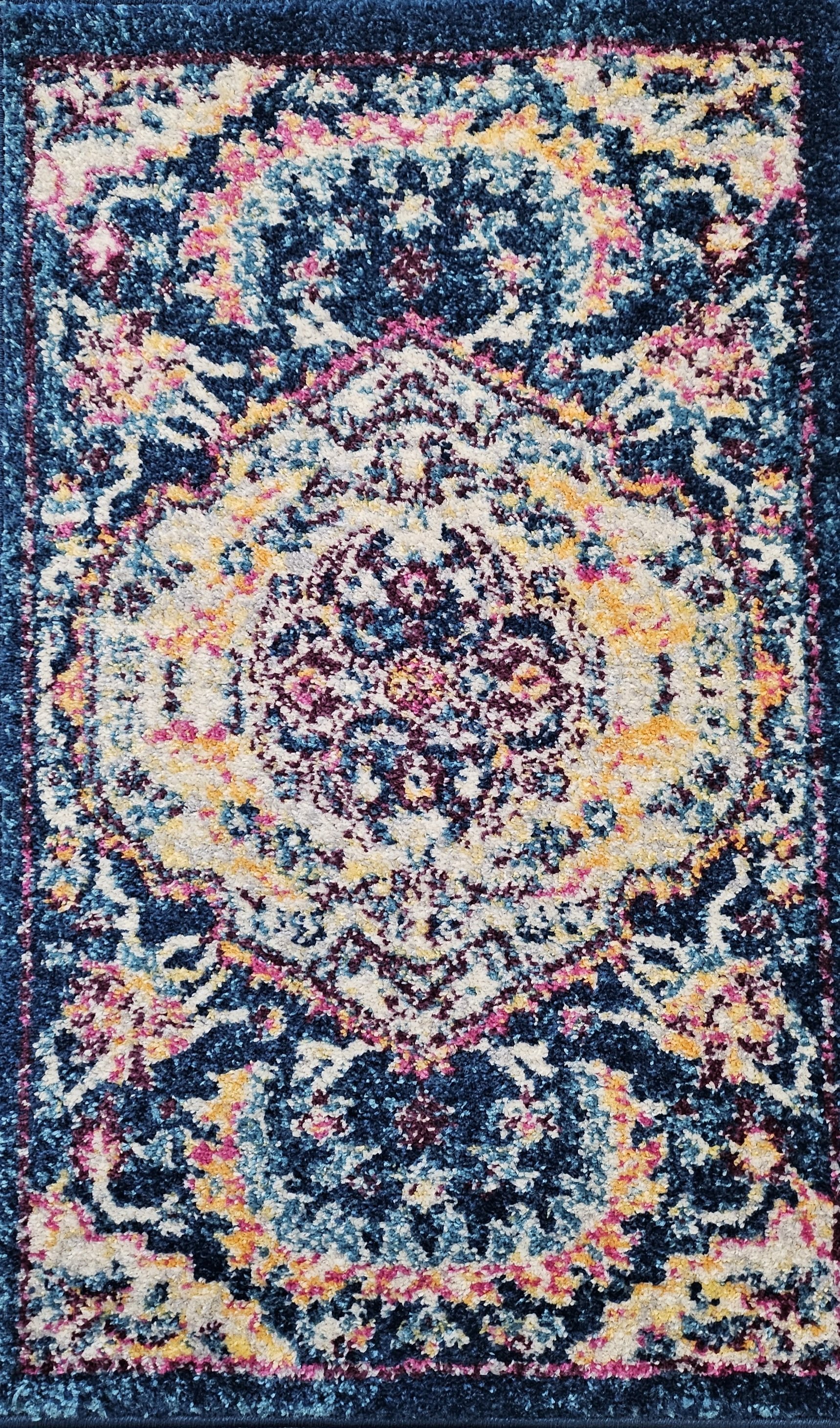 A colorful, patterned area rug with intricate floral and geometric designs in shades of blue, pink, yellow, and white.