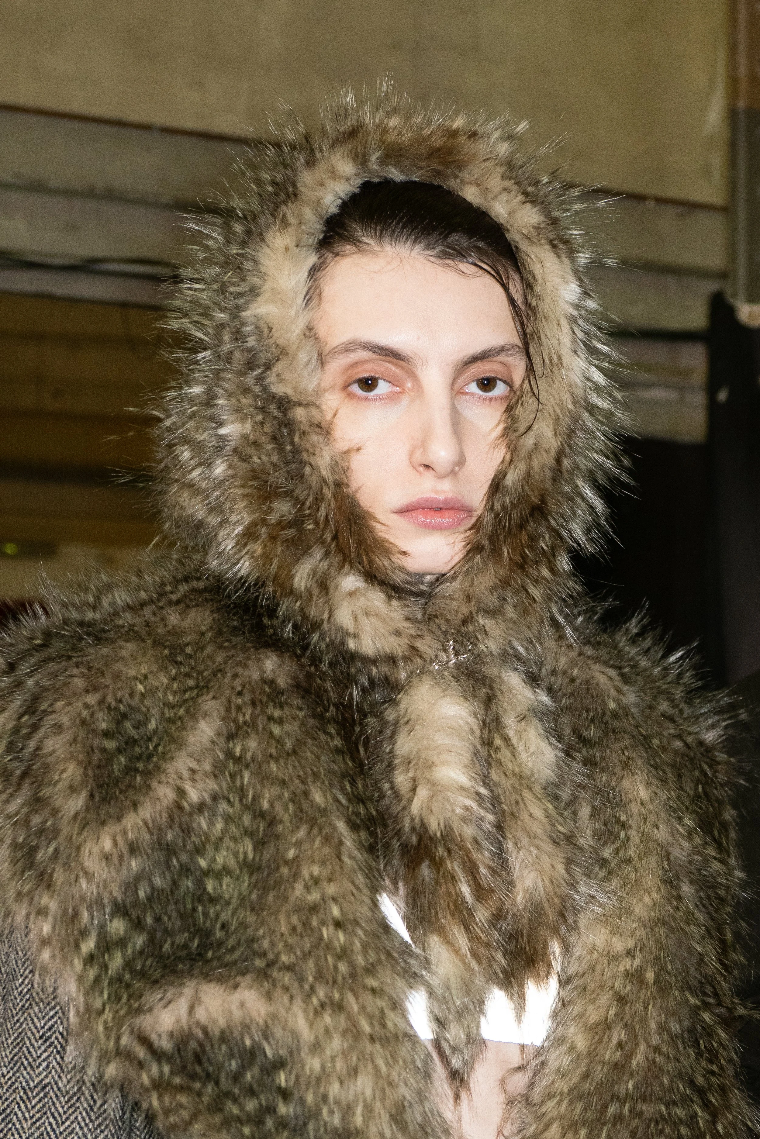 Person wearing a fur hooded coat with a serious expression.