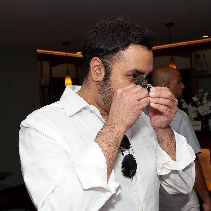 Man in white shirt taking a photograph with a camera, in a restaurant or cafe setting.