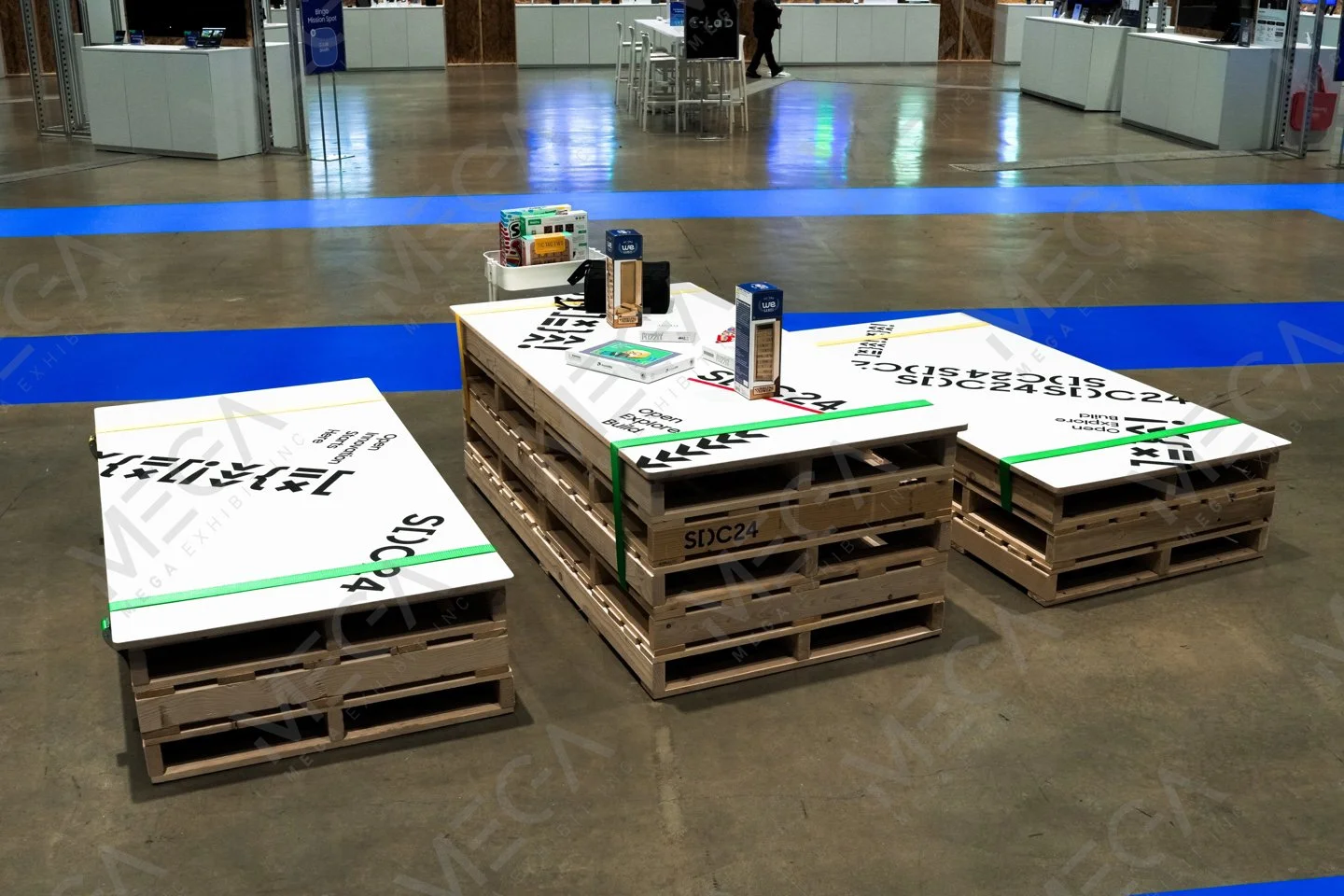 Displays of branded electronic accessories on wooden pallets with large printed signs, for Samsung's SDC 2024.