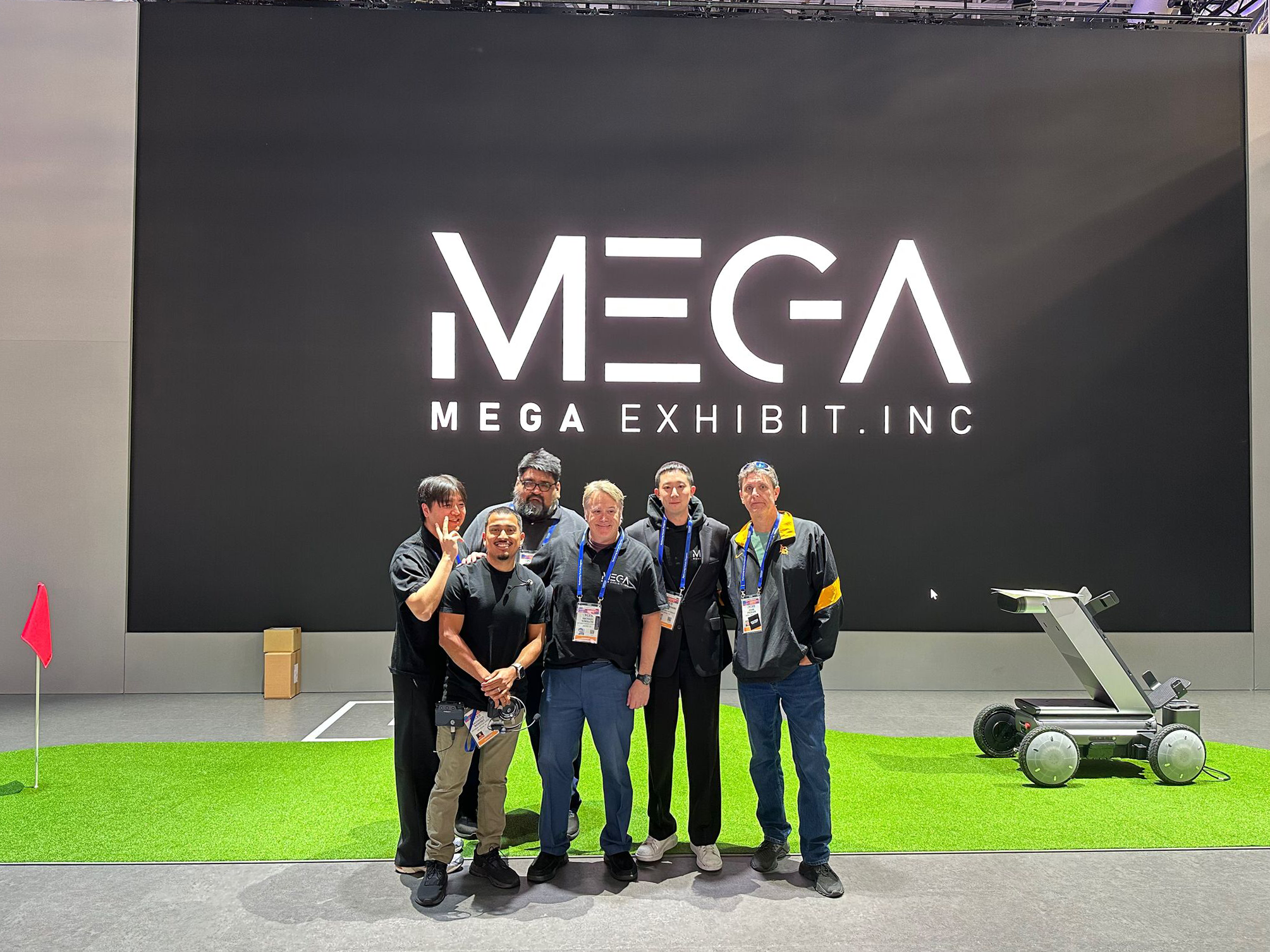 A photo of 6 of MEGA Exhibit's team members in front of the 2026 CES Hyundai booth with a large LED wall in the background displaying the MEGA Exhibit logo.