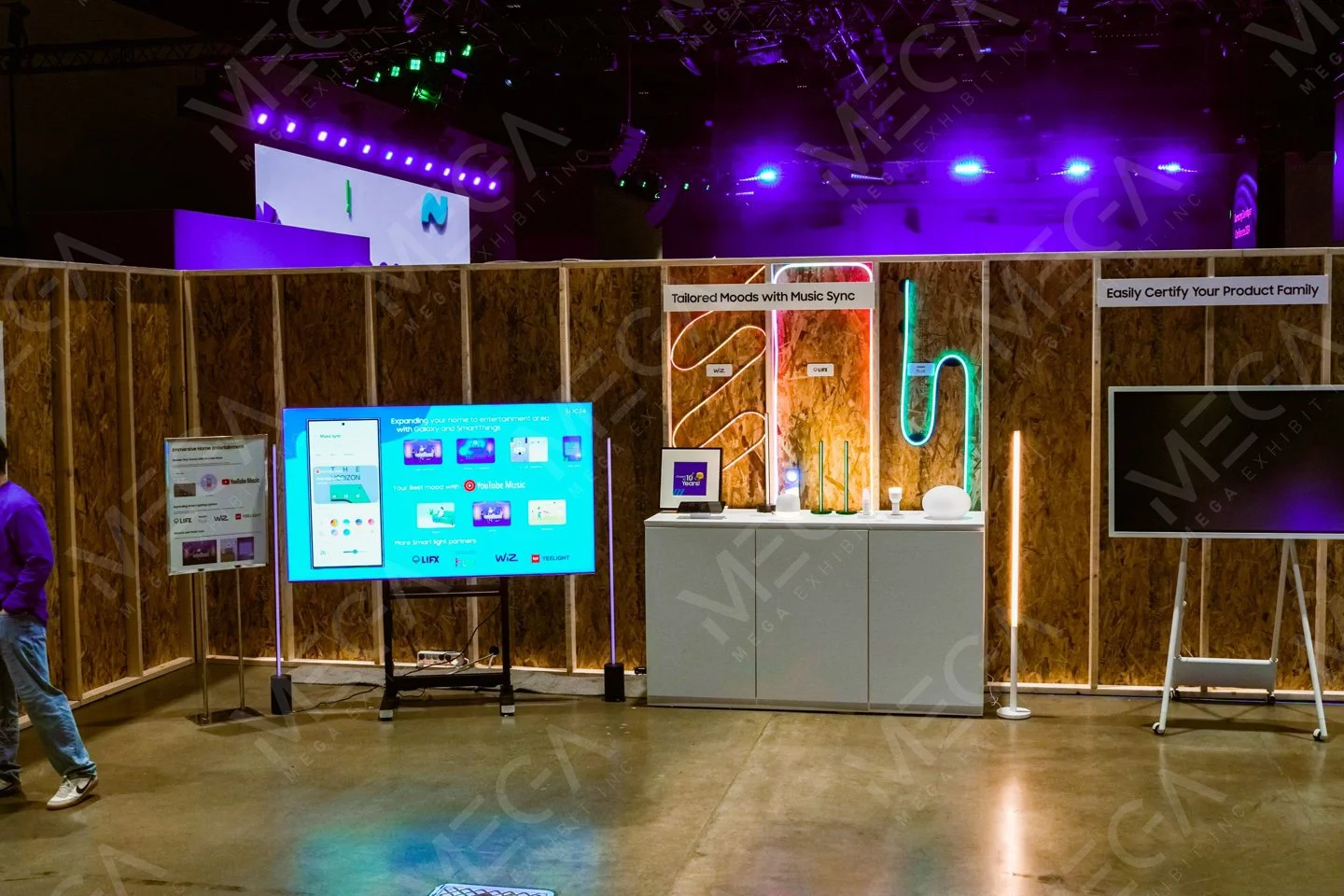 Trade show exhibit booth for Samsung's SDC 2024 with electronic displays, LED light installations, and a wooden partition wall.