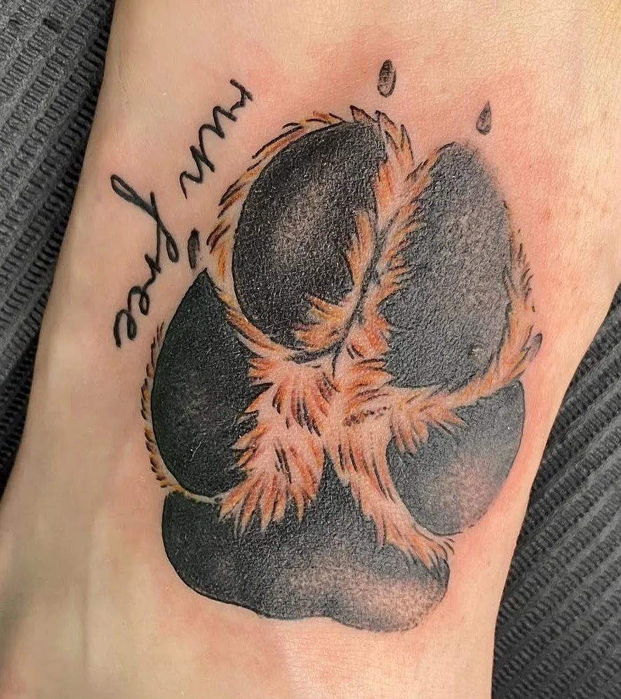 Tattoo of a realistic flower with black petals and orange highlights, accompanied by handwritten text that reads 'you got this'.