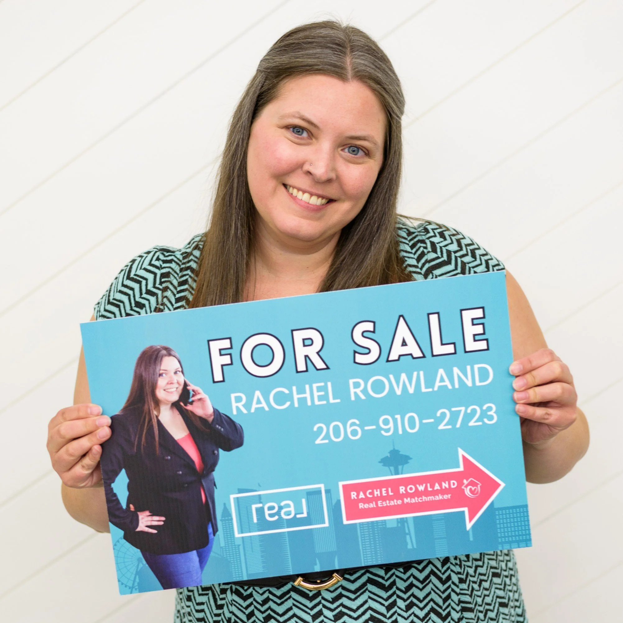 Woman holding a for sale sign featuring a photo of Rachel Rowland, a real estate matchmaker, with contact details and branding.