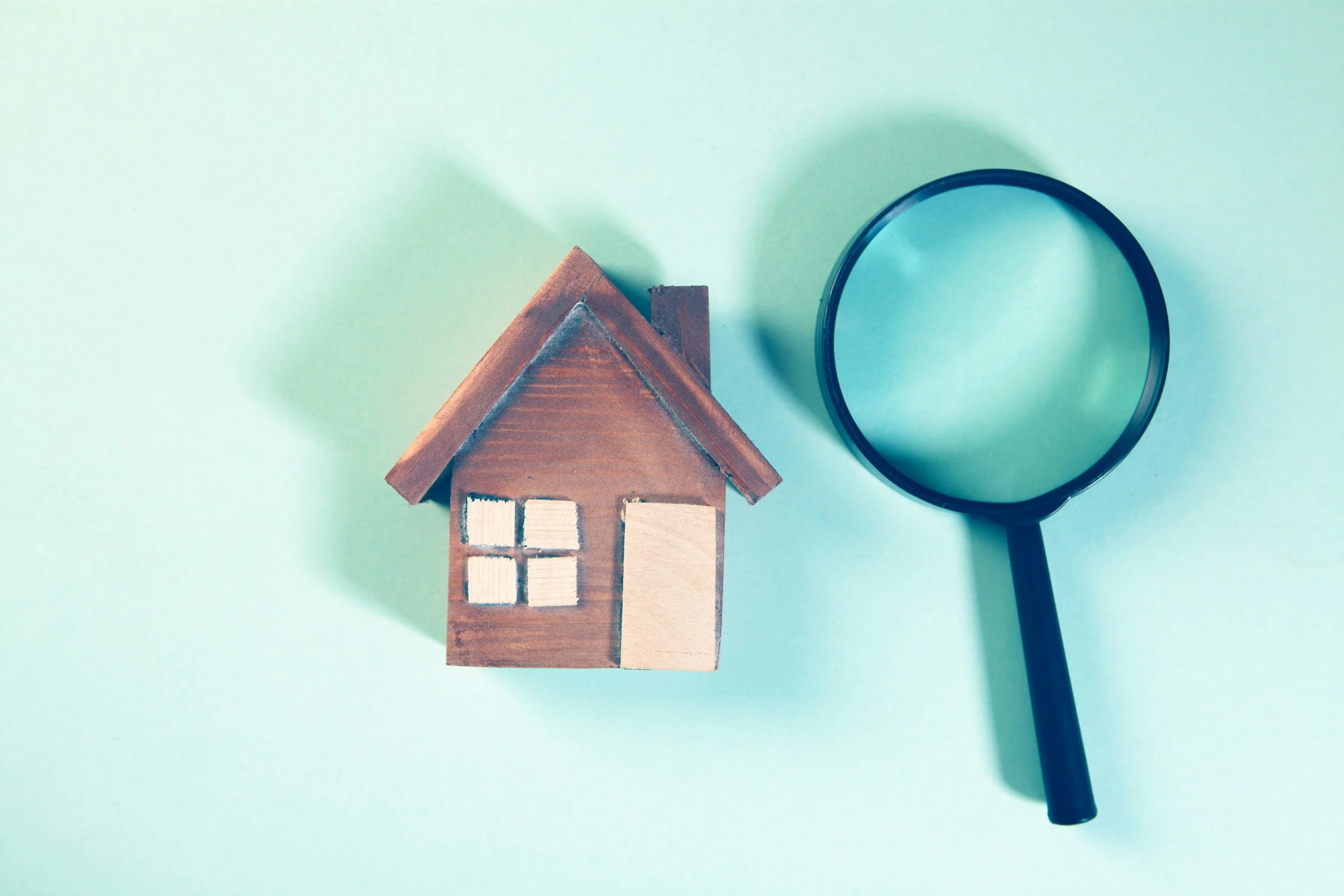 Small wooden house and a magnifying glass to represent home inspections.