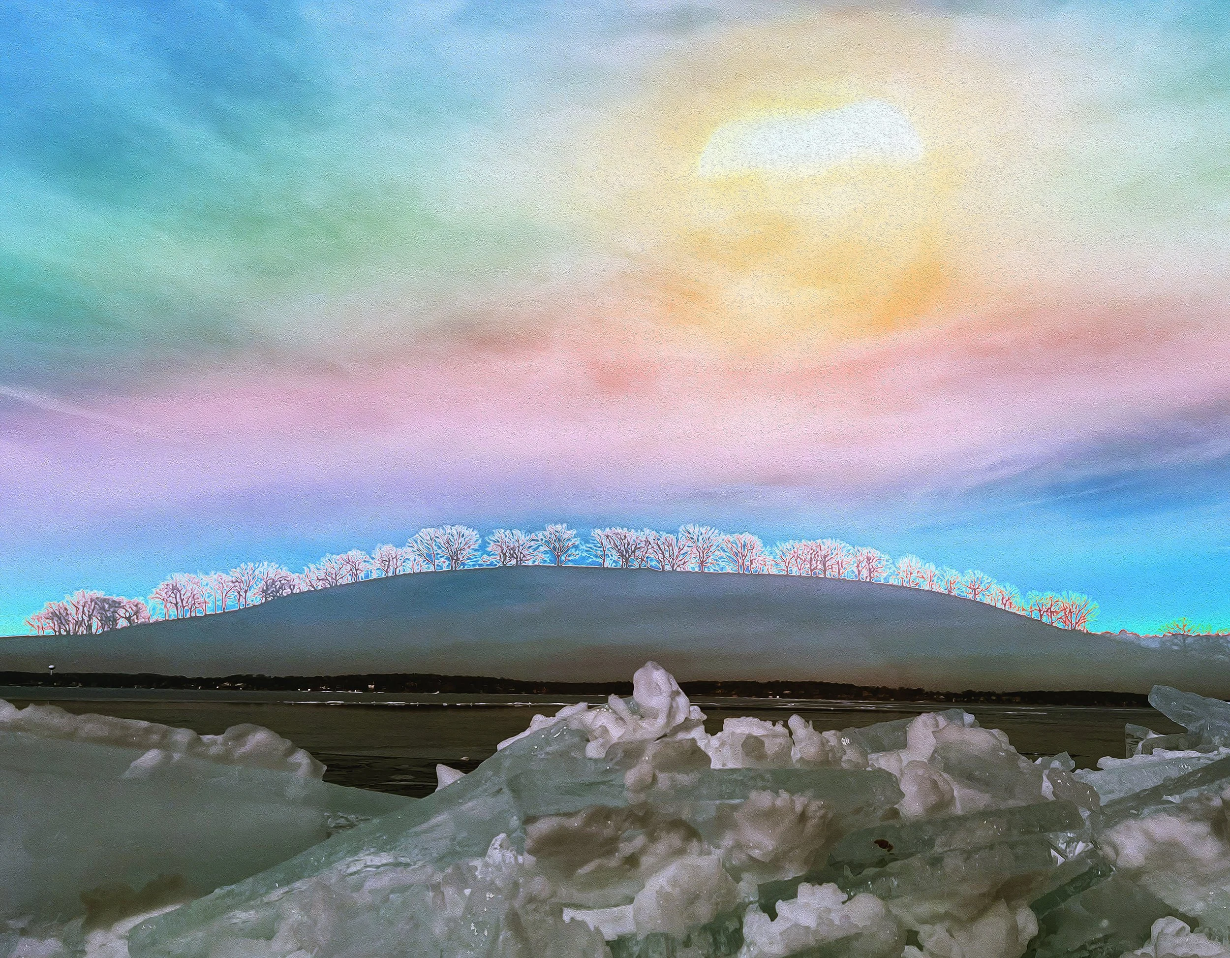 Colorful sunset sky over a row of leafless trees on a hill with snow in the foreground.