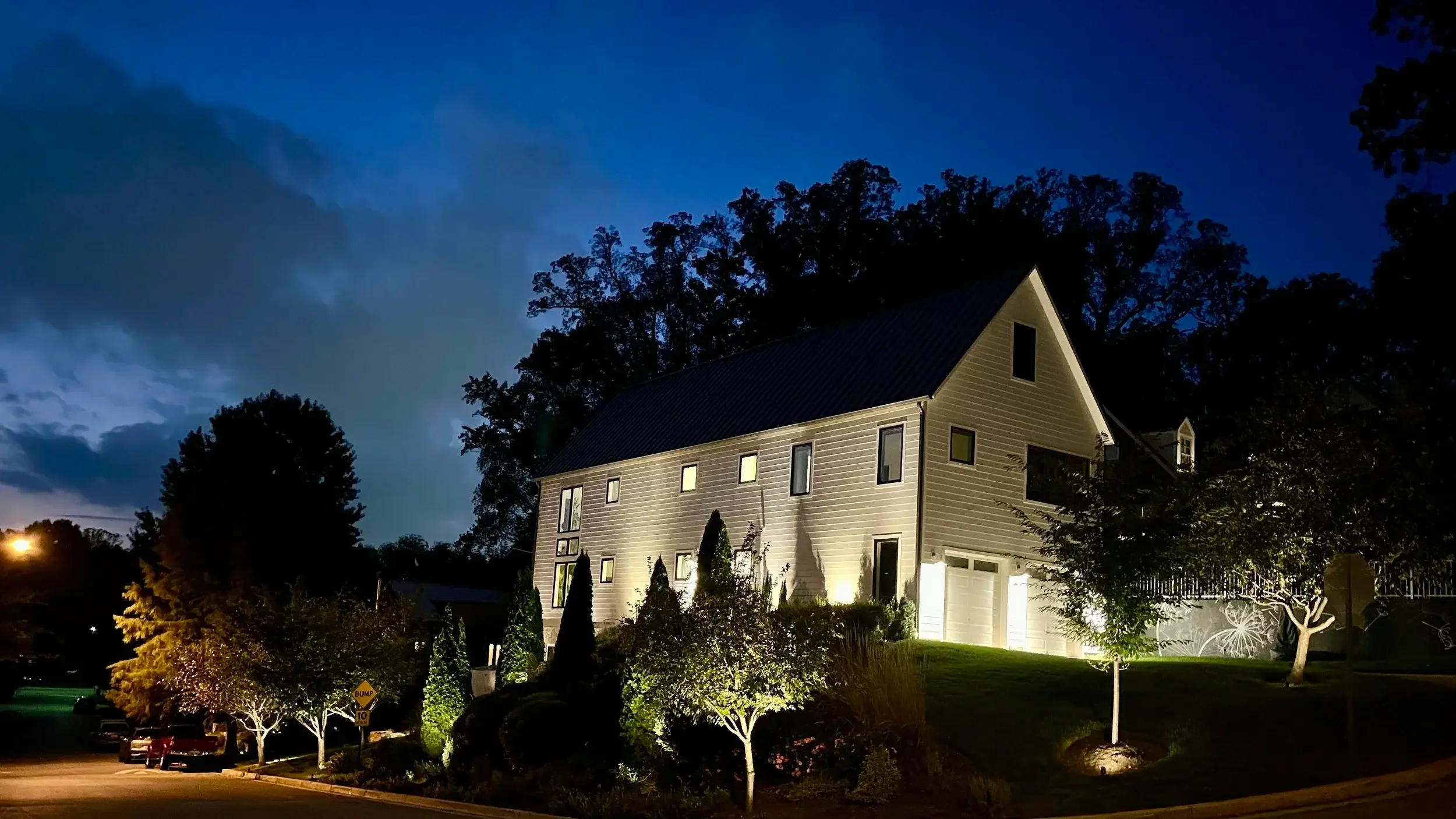 Dramatic uplighting highlights the clean lines and modern design of this charming home, creating a striking nighttime ambiance.
