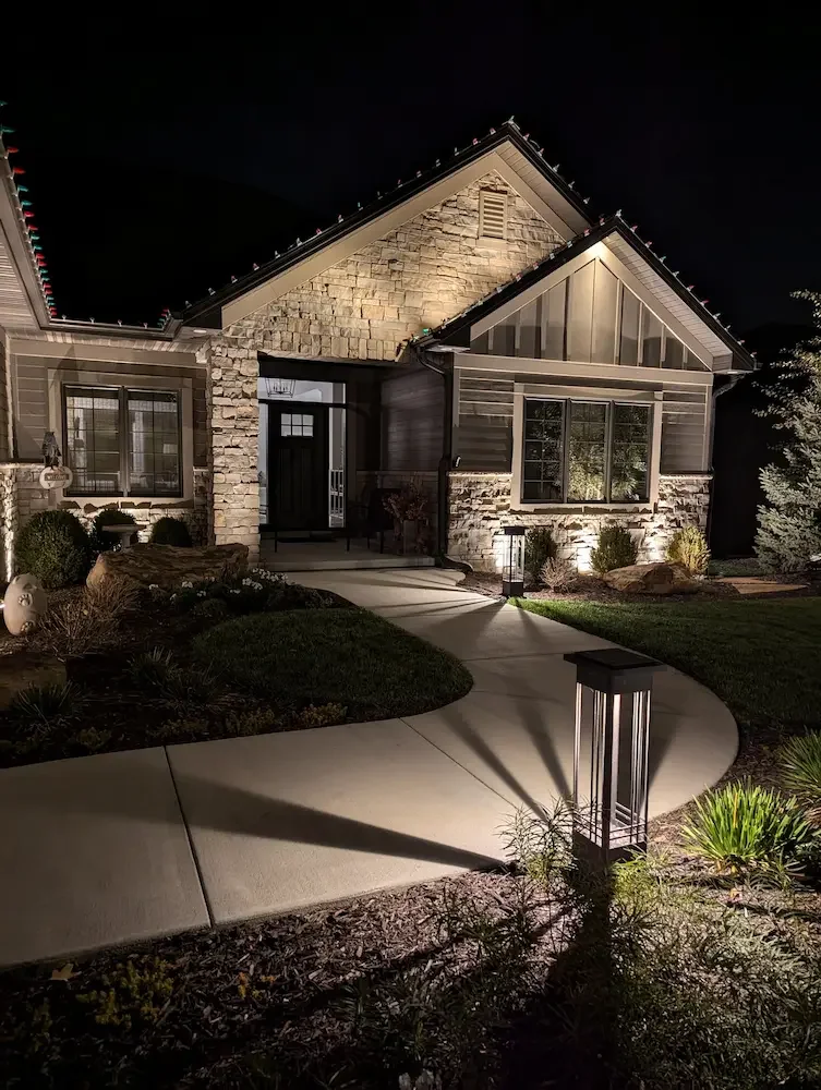 Warm light washes the stone facade, bringing out it's texture. Bollard lights play with light and shadows to beautifully enhance safety and provide practical lighting.