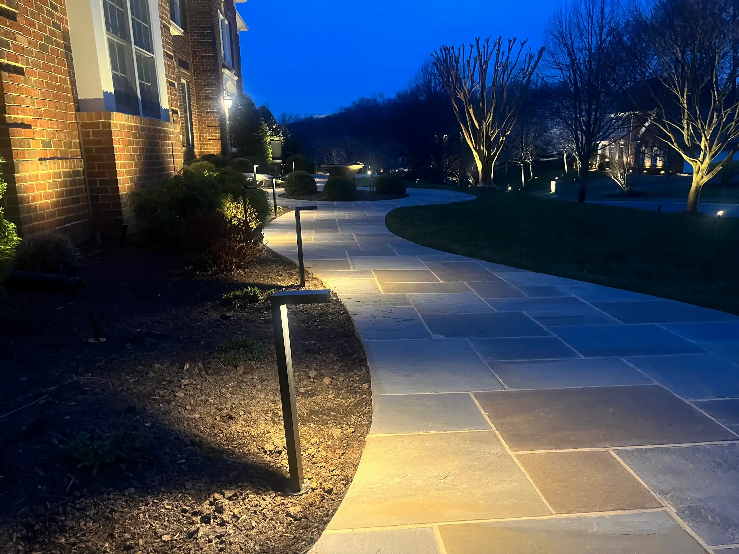 Landscape lighting guiding a front walkway toward an illuminated home entrance