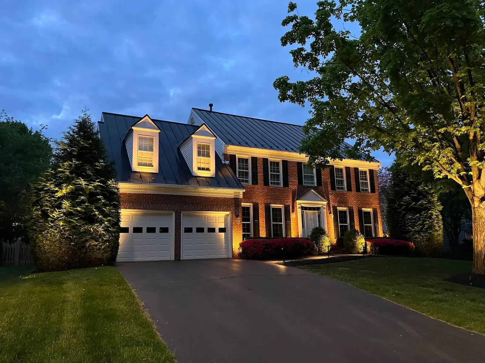 The architectural details and lanscaping of this red brick home and illuminated with warm uplighting.
