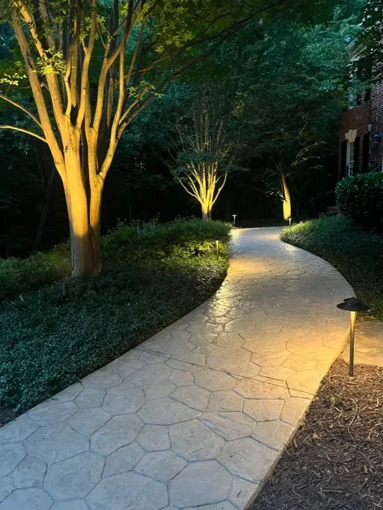 Brass path lights illuminated stamped concrete path to a Leesburg estate.