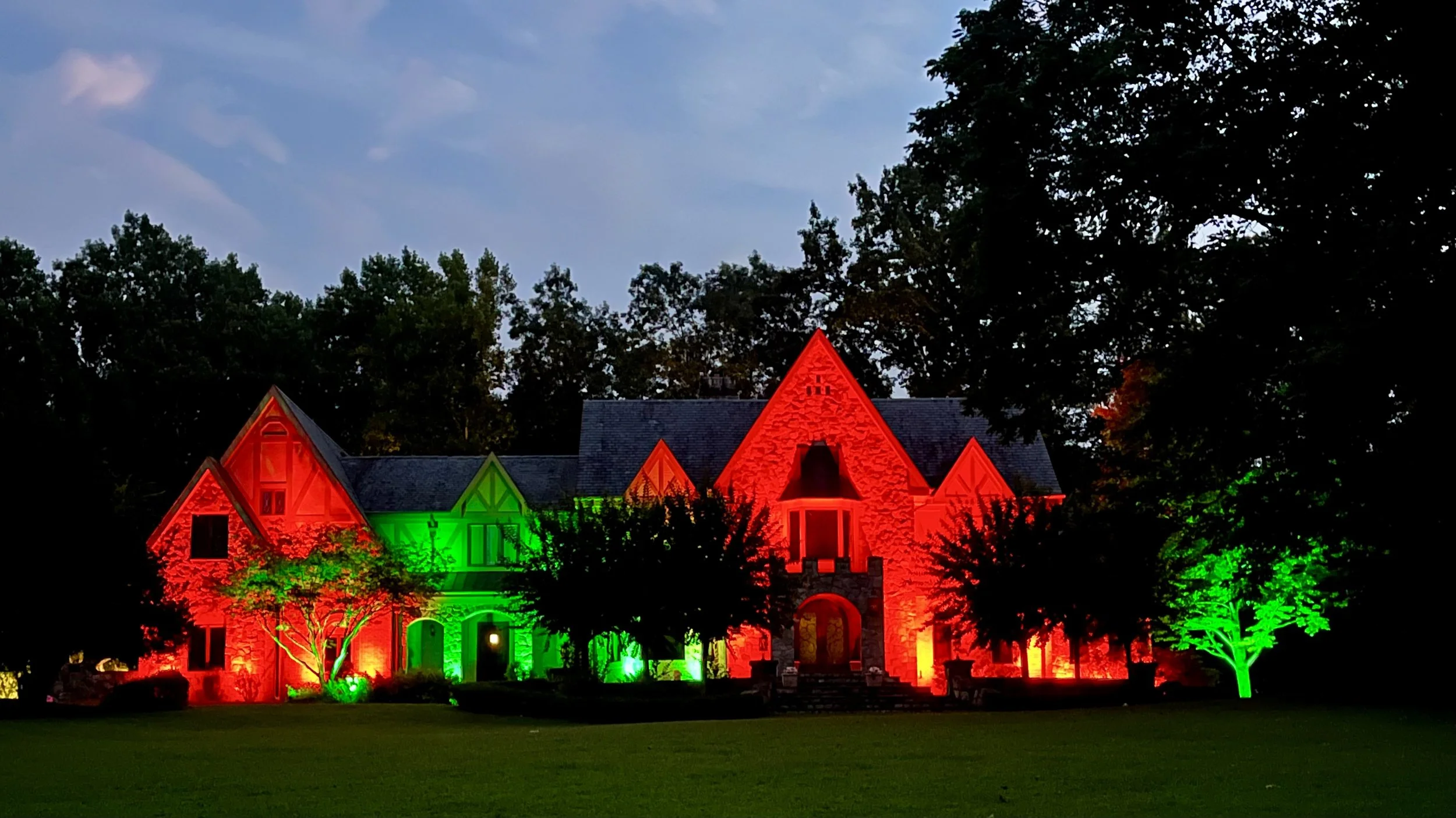 Front façade illuminated in red and green holiday lighting using a programmable architectural outdoor lighting system.