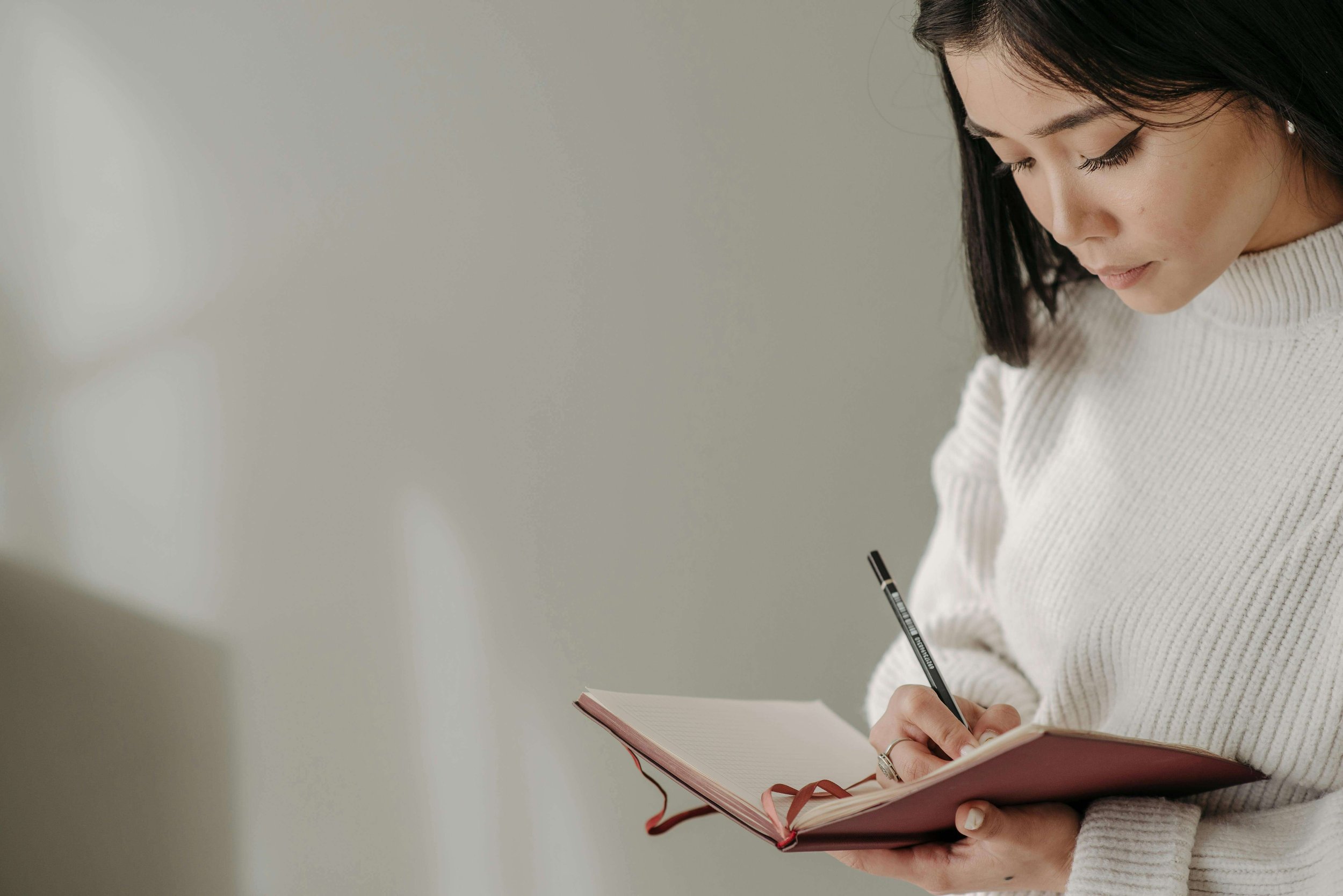 Woman writing in a journal, processing her thoughts after a tough day — a therapist for perfectionism in Garden City, New York offers perfectionism treatment in Garden City, NY to help you stop spiraling and start leading.