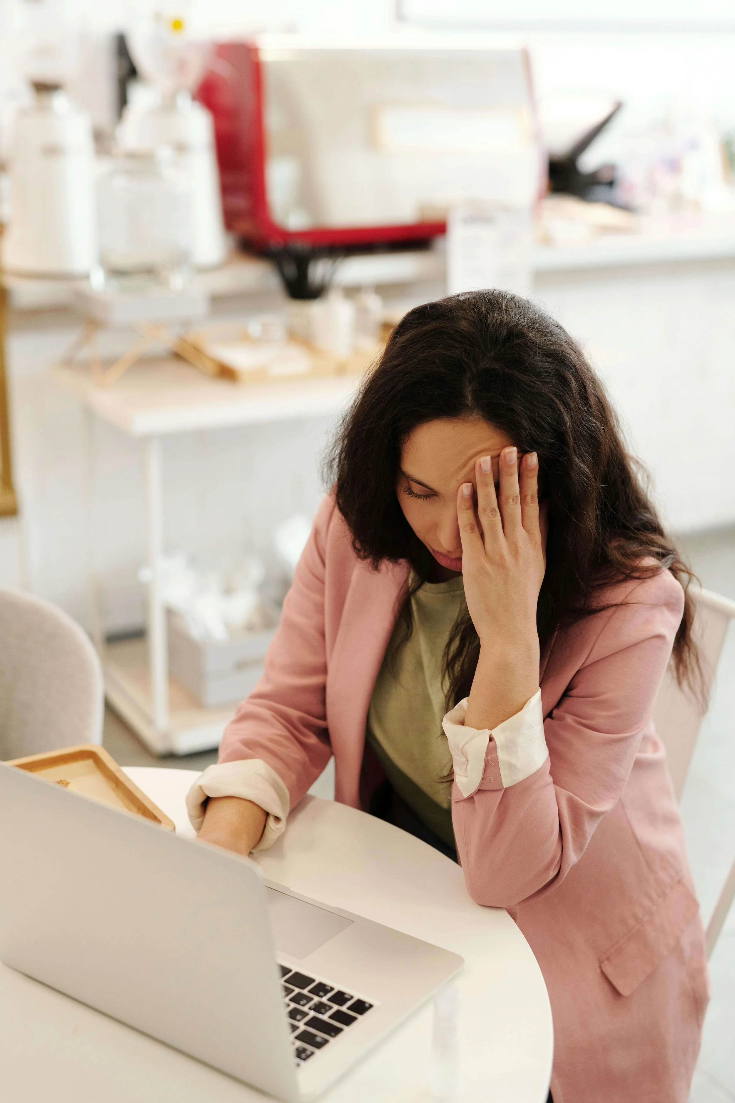 Woman at her laptop with her hand on her face, overwhelmed by self-doubt — perfectionist therapy in Garden City, NY and perfectionism treatment in Garden City, NY help you move beyond imposter syndrome.