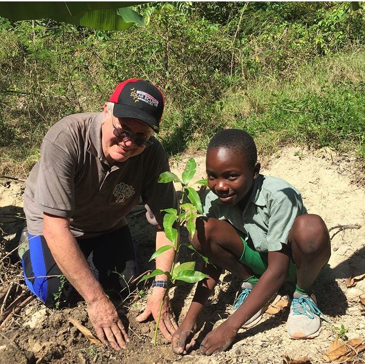 Student and volunteer planting sapling in Port-Au-Prince