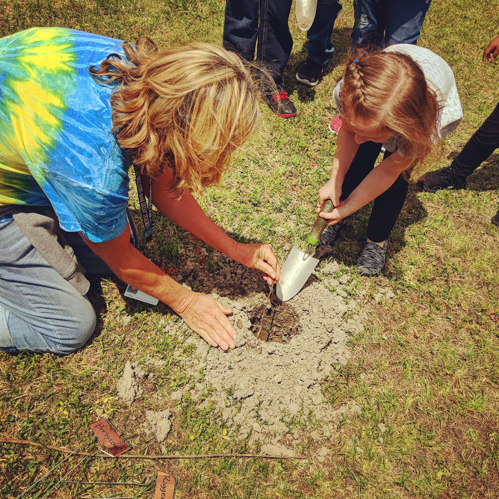 Teacher and student planting sapling