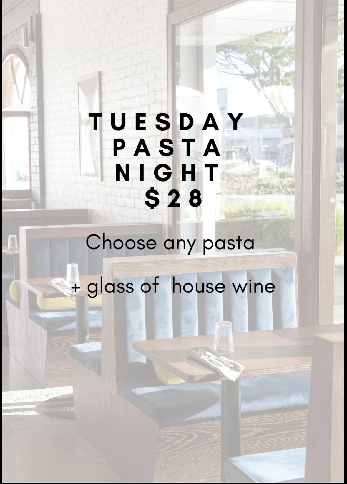 Restaurant window with promotional sign offering Tuesday pasta night for $28, includes any pasta and a glass of house wine, with visible tables and chairs inside.