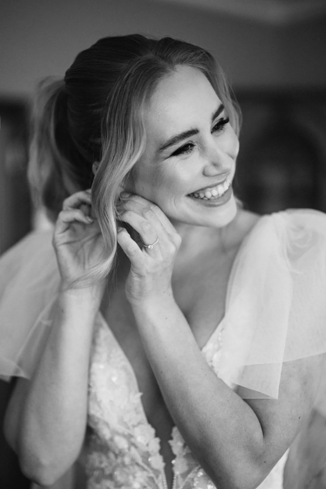 black and white close up of bride smiling putting in ear-ring