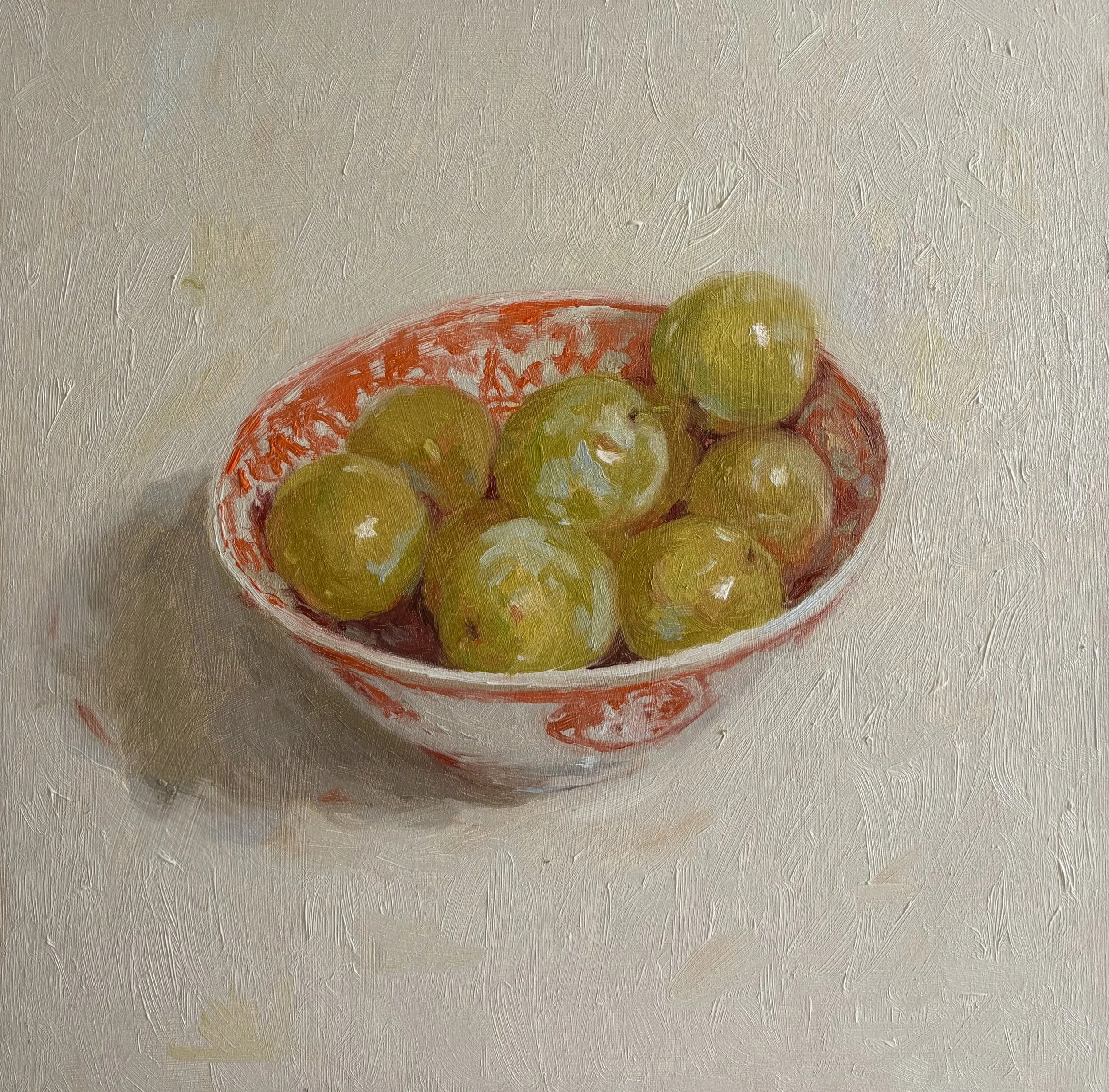 Green plums in an Orange Bowl