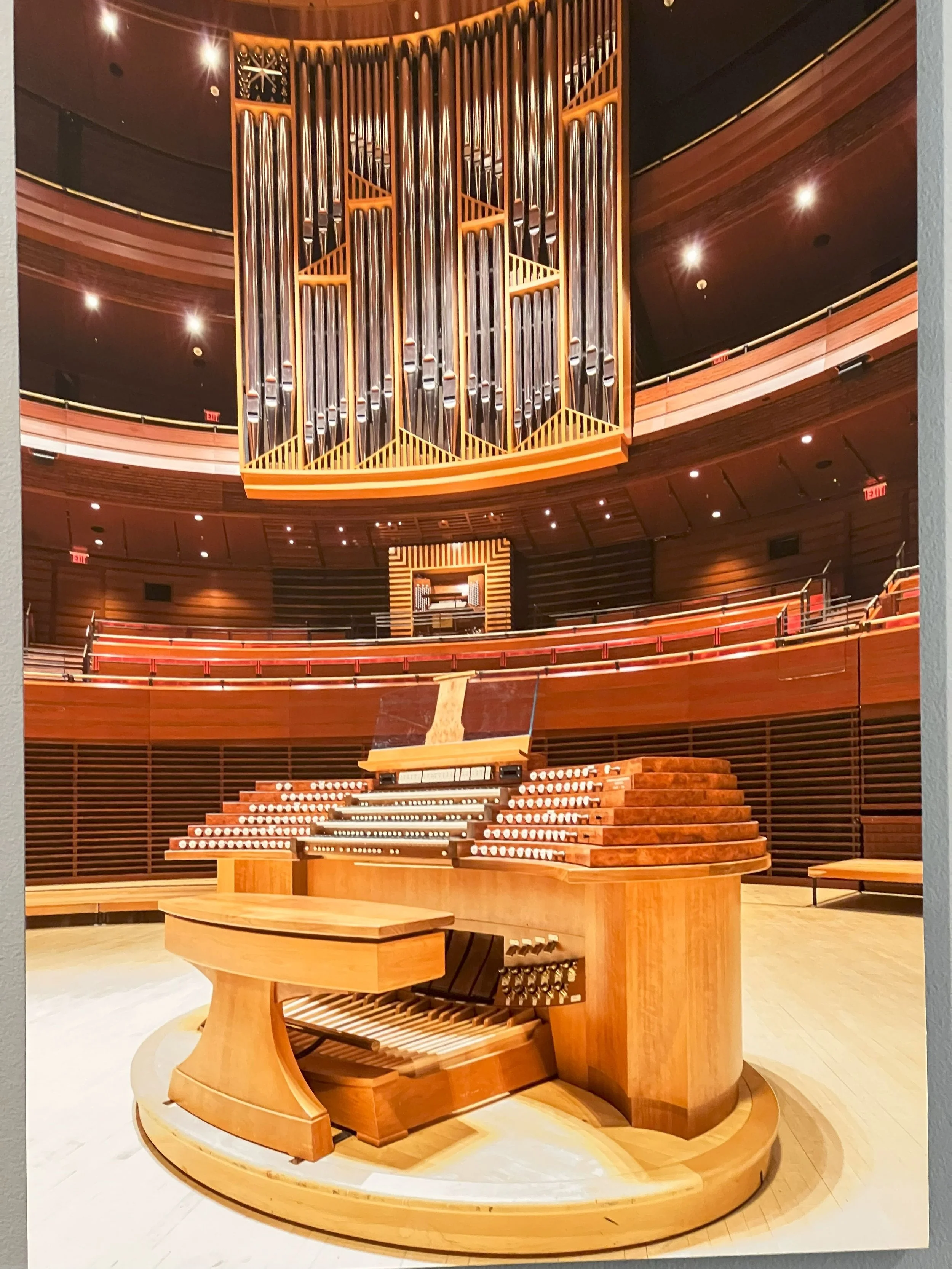Another performance hall organ installation. The main console in the foreground can be moved offstage to create room for additional performers. The organist then uses the secondary console, pictured in the balcony behind the main console.