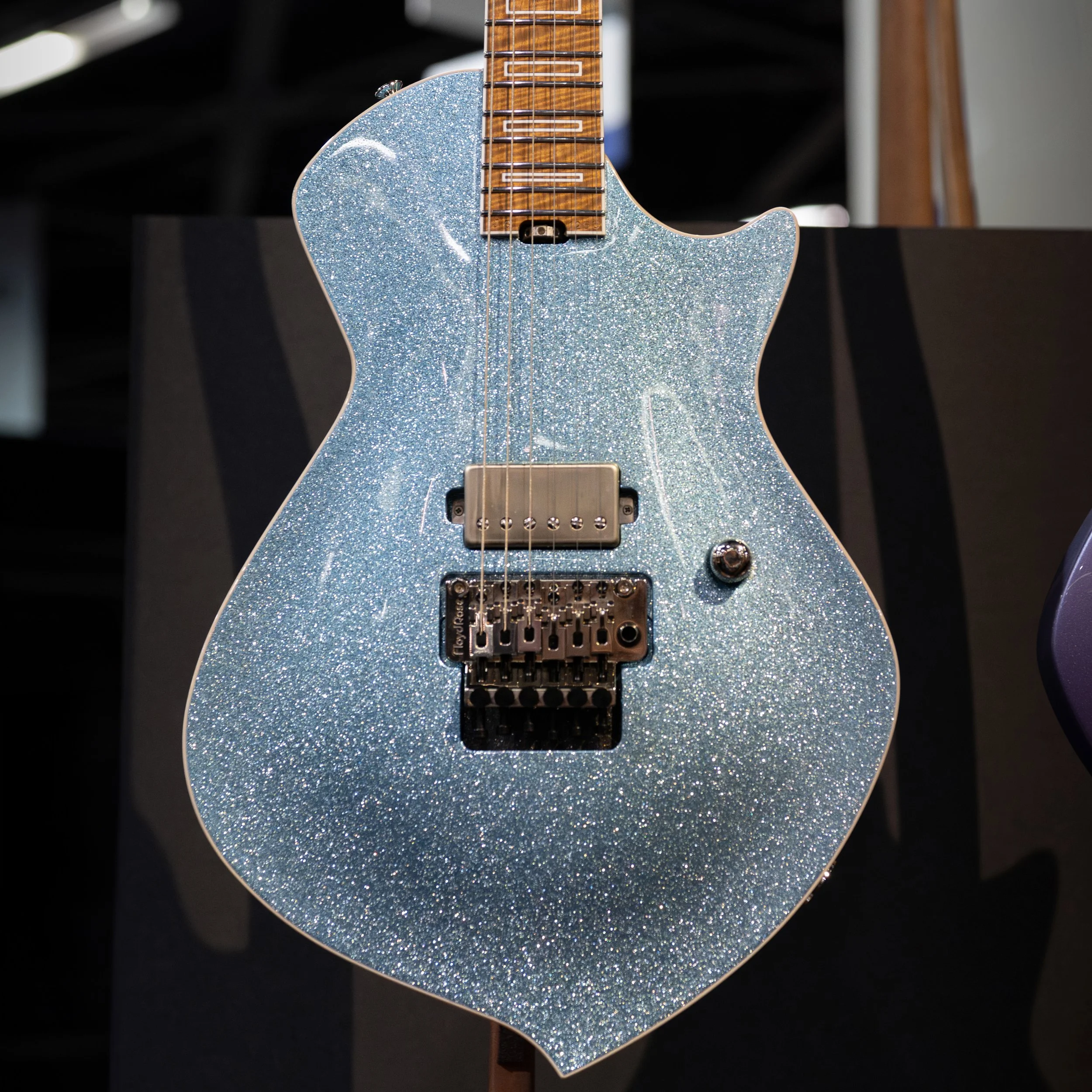 Electric Sully guitar with a glittery blue finish and a wooden neck.