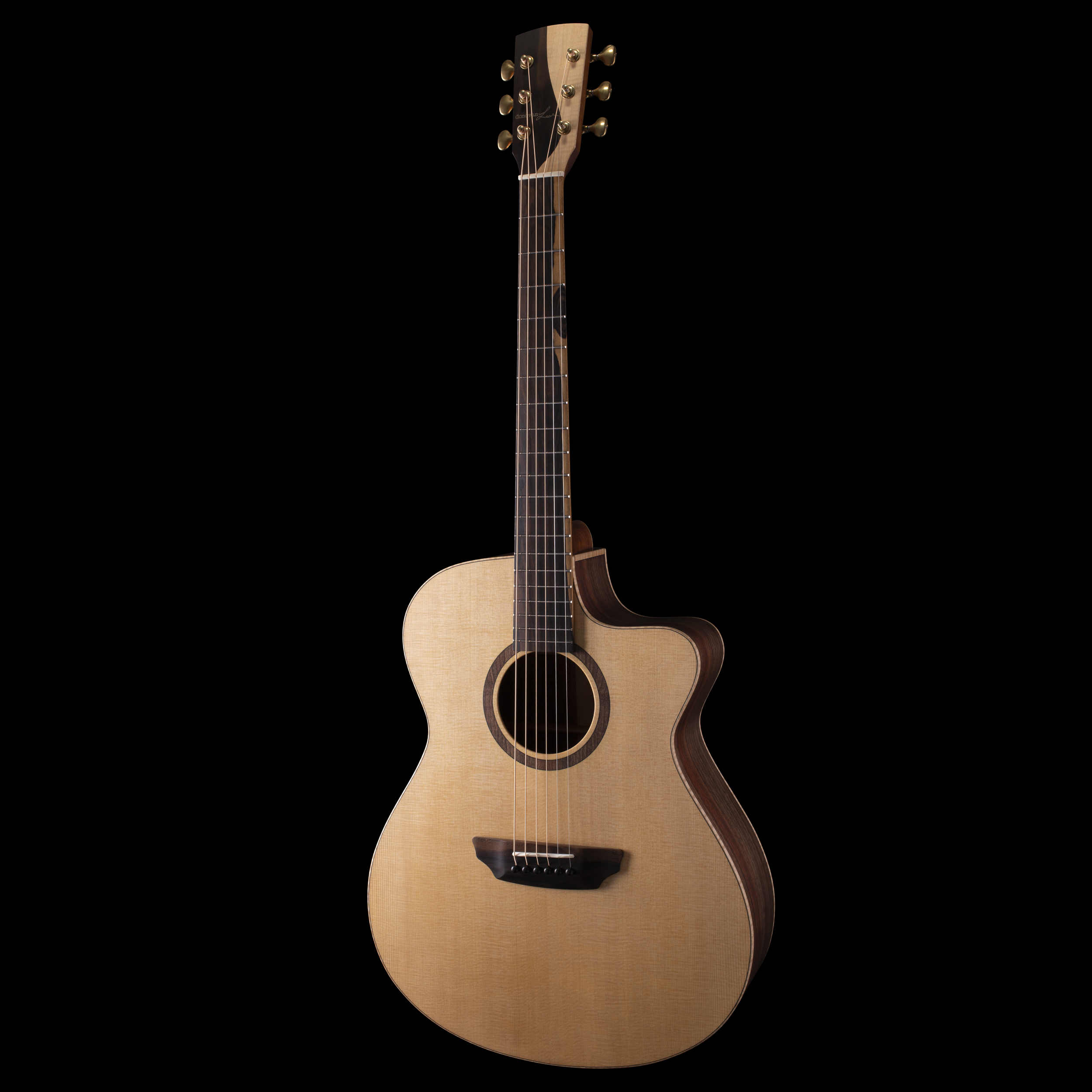A Donovan Leah acoustic Caroline guitar with a light-colored body, dark fretboard, and gold tuning pegs, isolated on a black background.