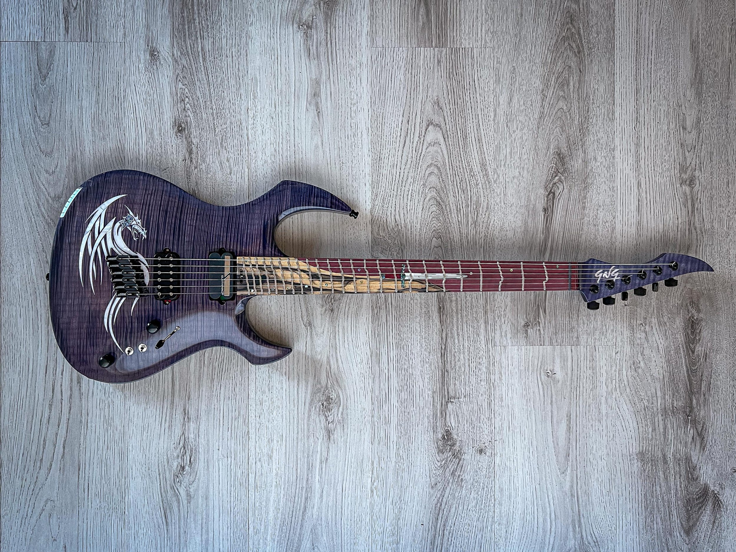 Black GNG Giulio Negrini electric guitar with a purple flame design on a wooden floor.