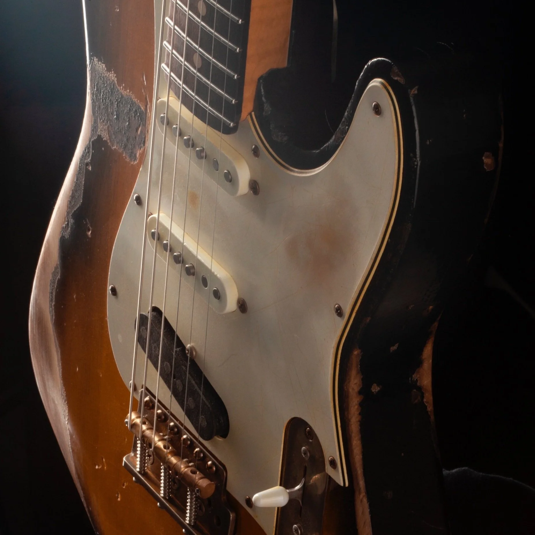Close-up of a B3 vintage style electric guitar with worn finish, showing pickups, strings, and bridge.