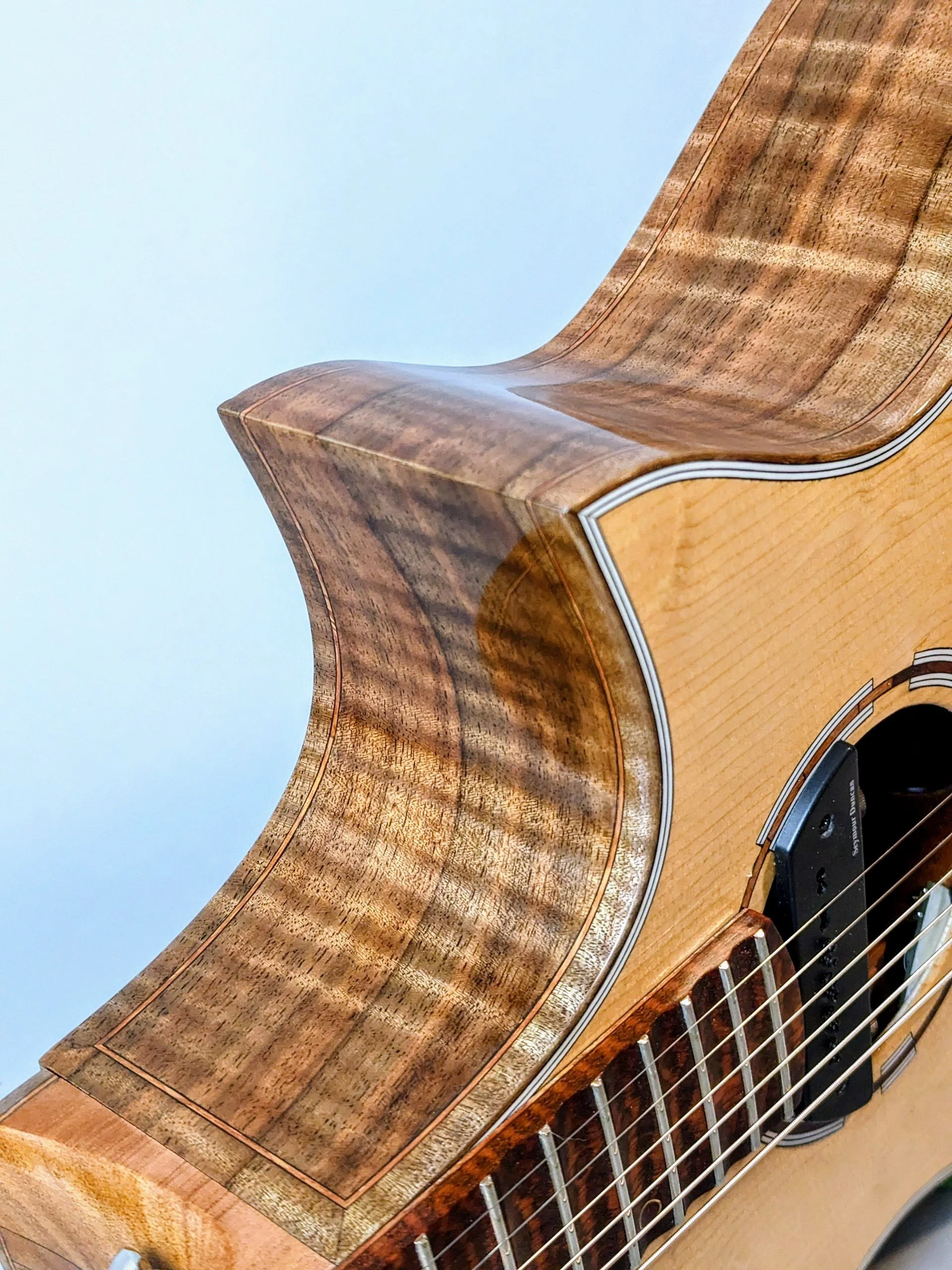 Close-up of a Morgan Kelsey acoustic guitar highlighting its wooden body and fretboard.