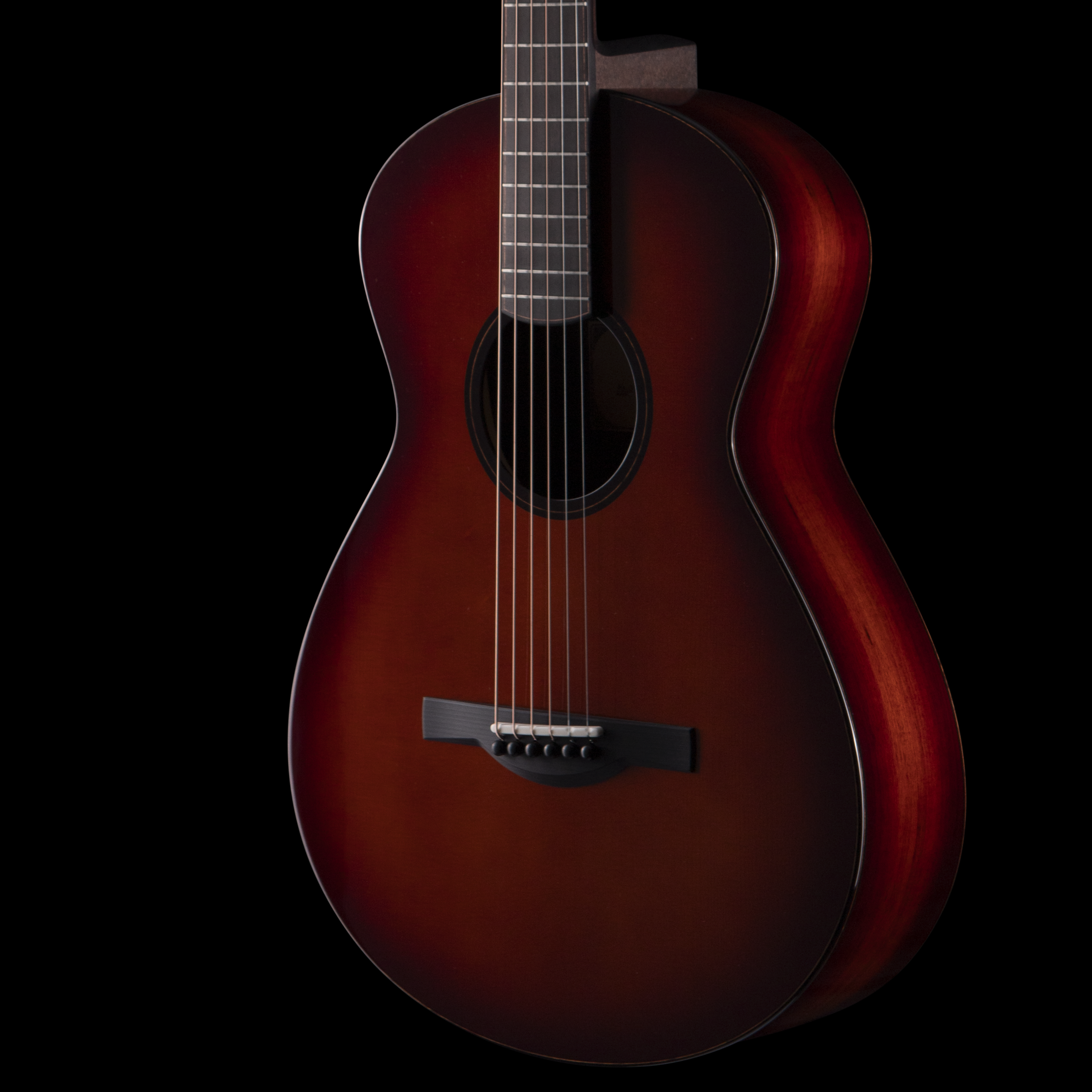 Close-up of a sunburst finish acoustic Dion guitar against a black background.