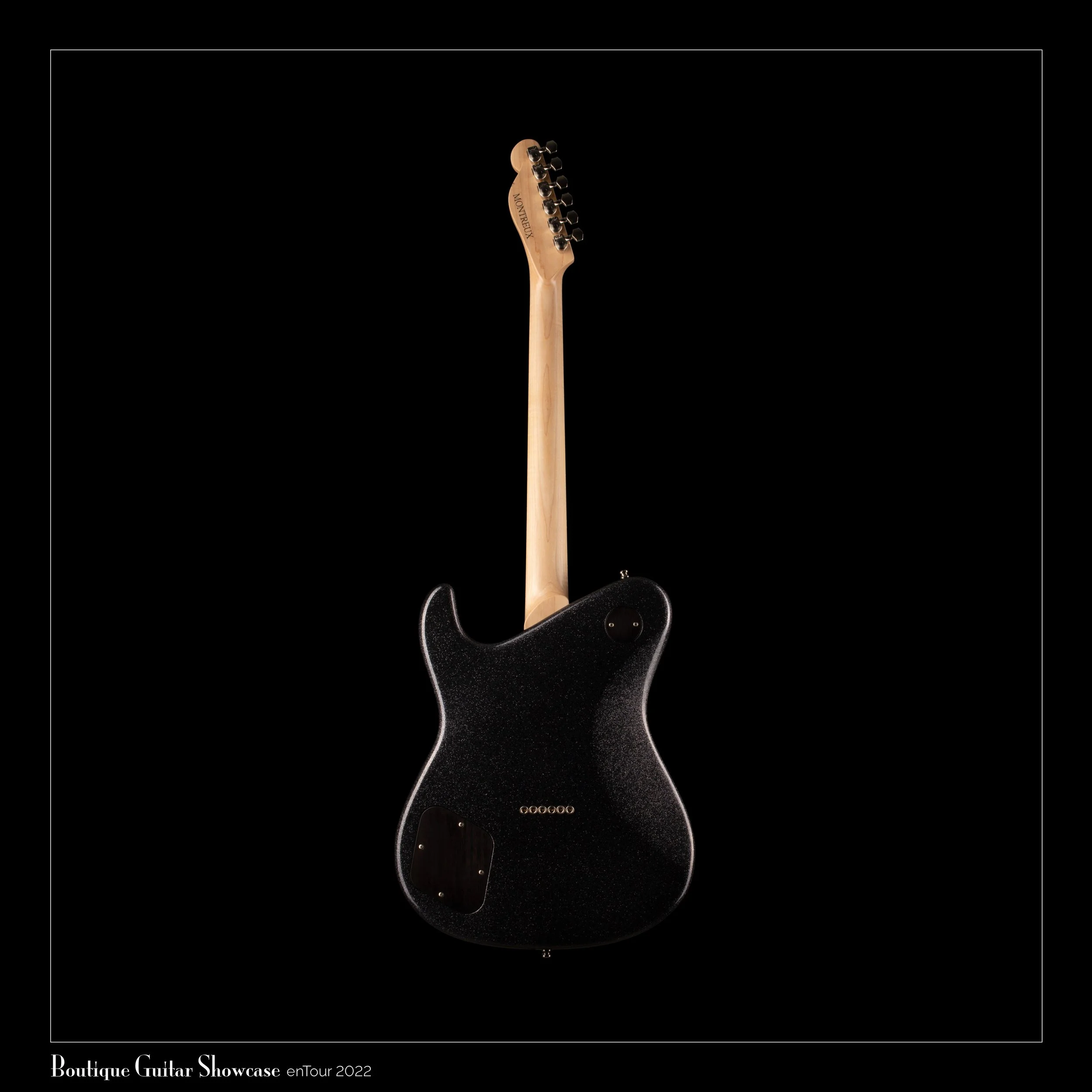 Black Tausch electric guitar with a natural wood neck displayed against a black background, part of a boutique guitar showcase at an enTour 2022 event.