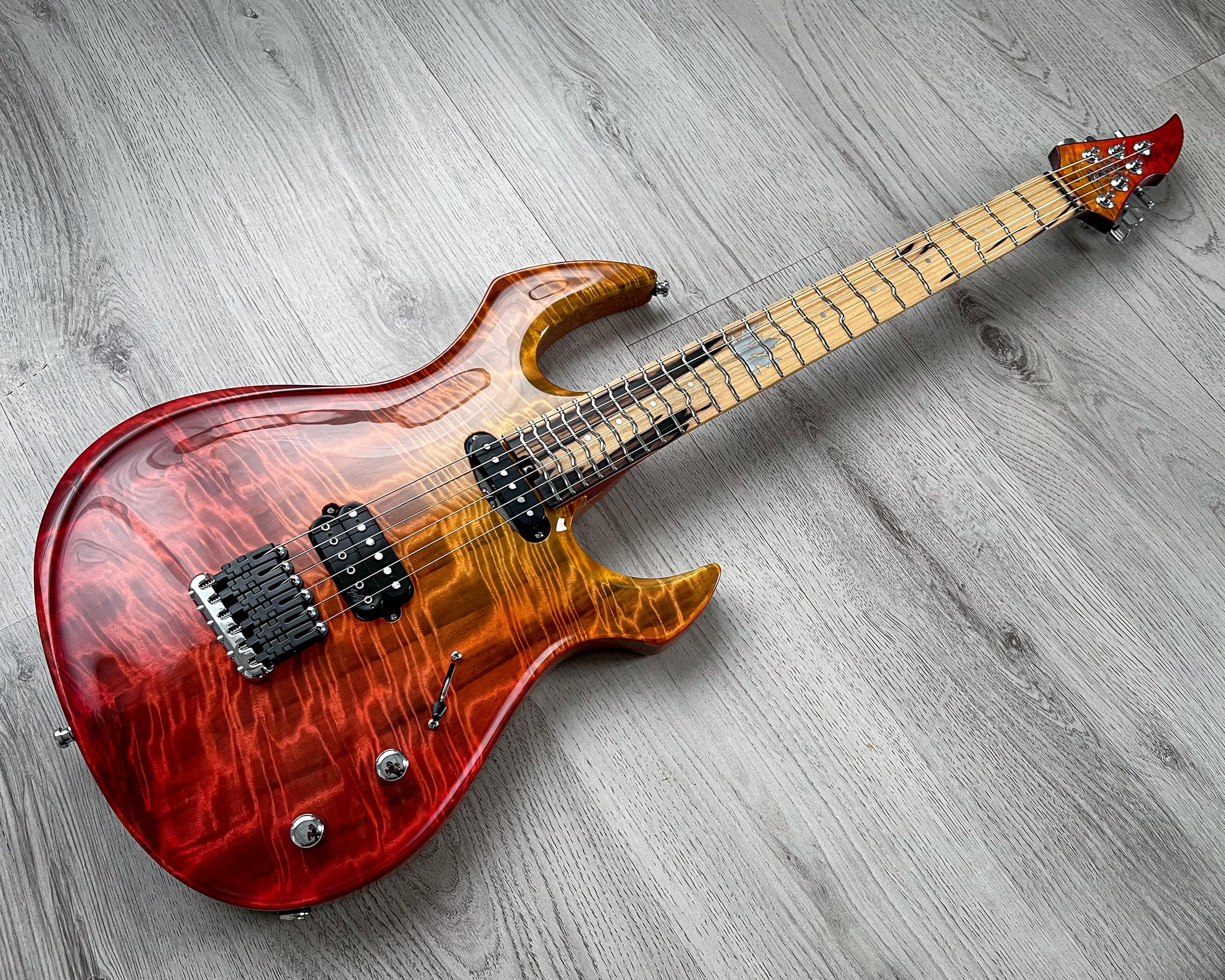 GNG Giulio Negrini red and orange electric guitar with a flame maple top resting on a light wood floor.
