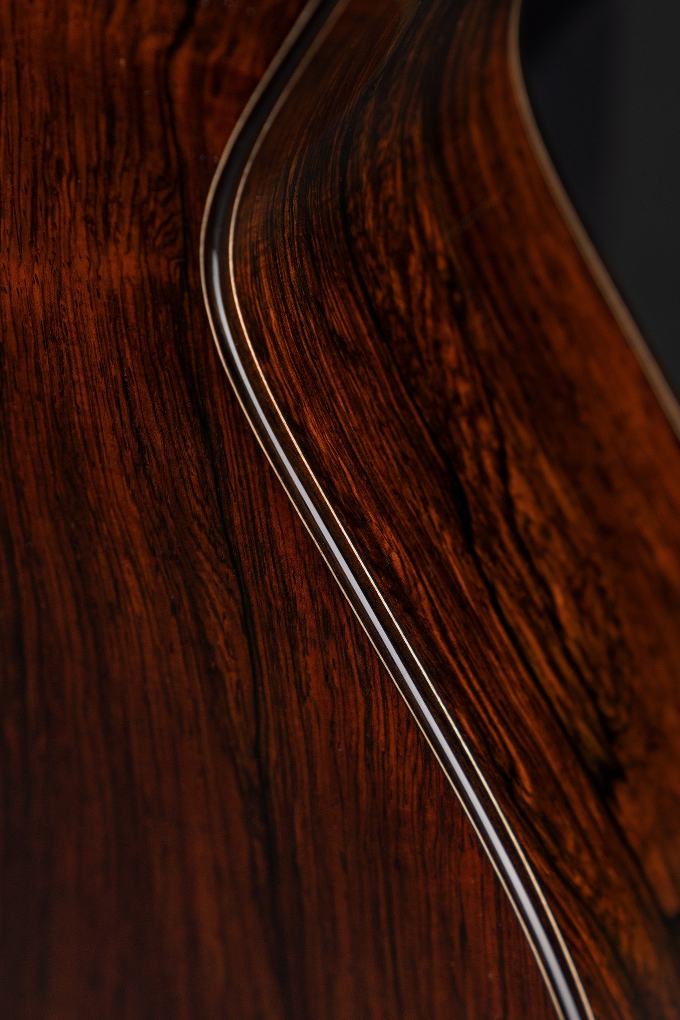 Close-up of an Isaac Jang guitar, showing the detailed grain and curvature of the wood.
