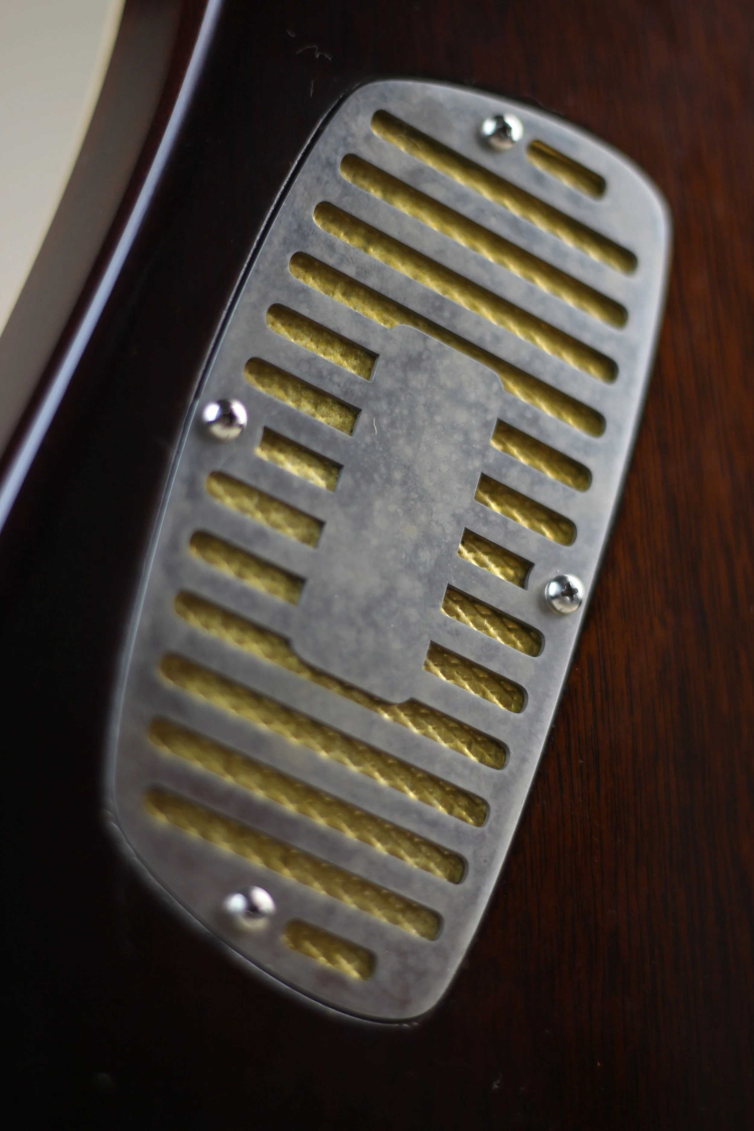 Close-up of a vintage Corsell electric guitar pickup with metal cover and yellow coil wire, mounted on a dark wood guitar body.