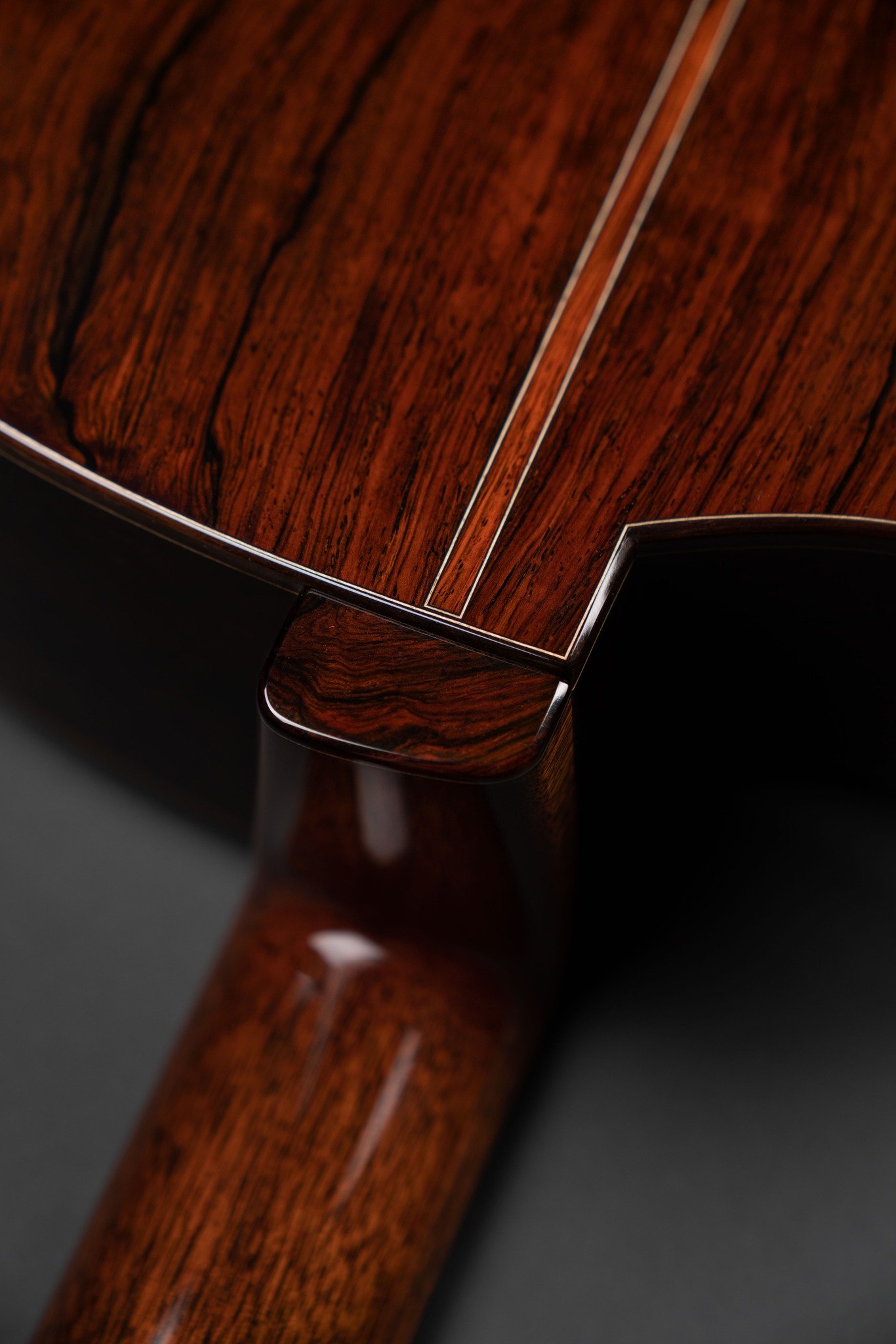Close-up of a polished back on an Isaac Jang guitar, showing rich grain patterns and a high-gloss finish.