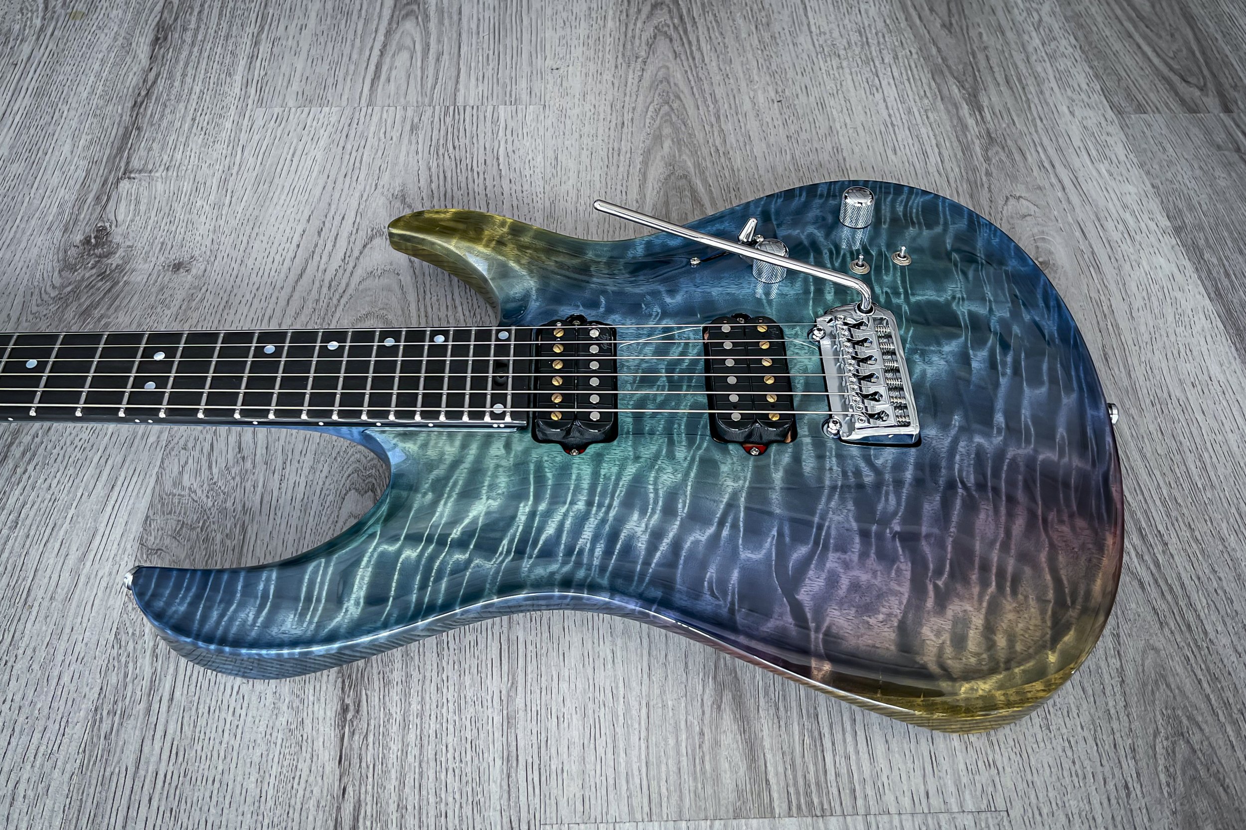 GNG Giulio Negrini electric guitar with a blue, green, and red gradient finish on a wooden floor.