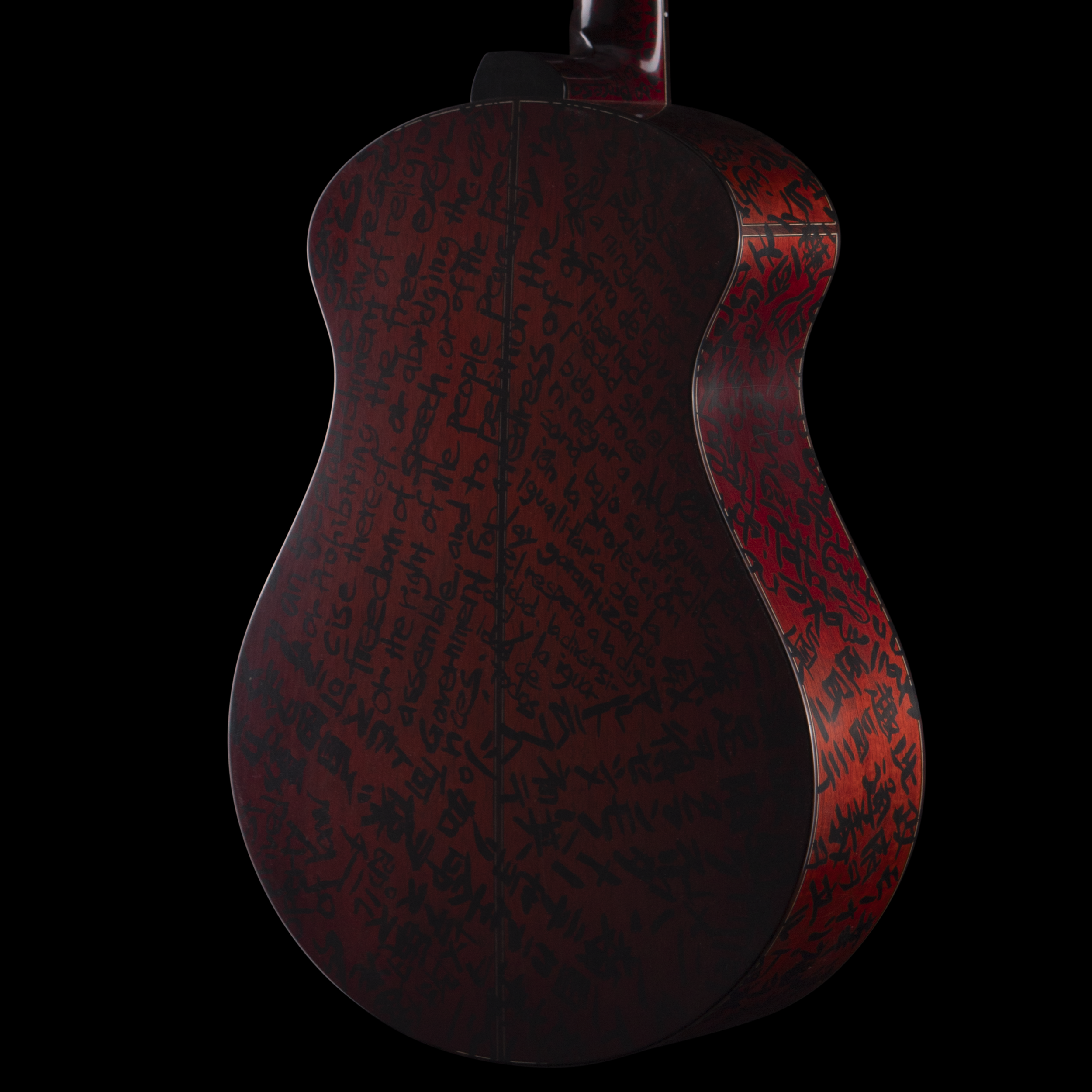 A Matsuda guitar with a dark red body featuring handwritten text in black, viewed from the back against a black background.