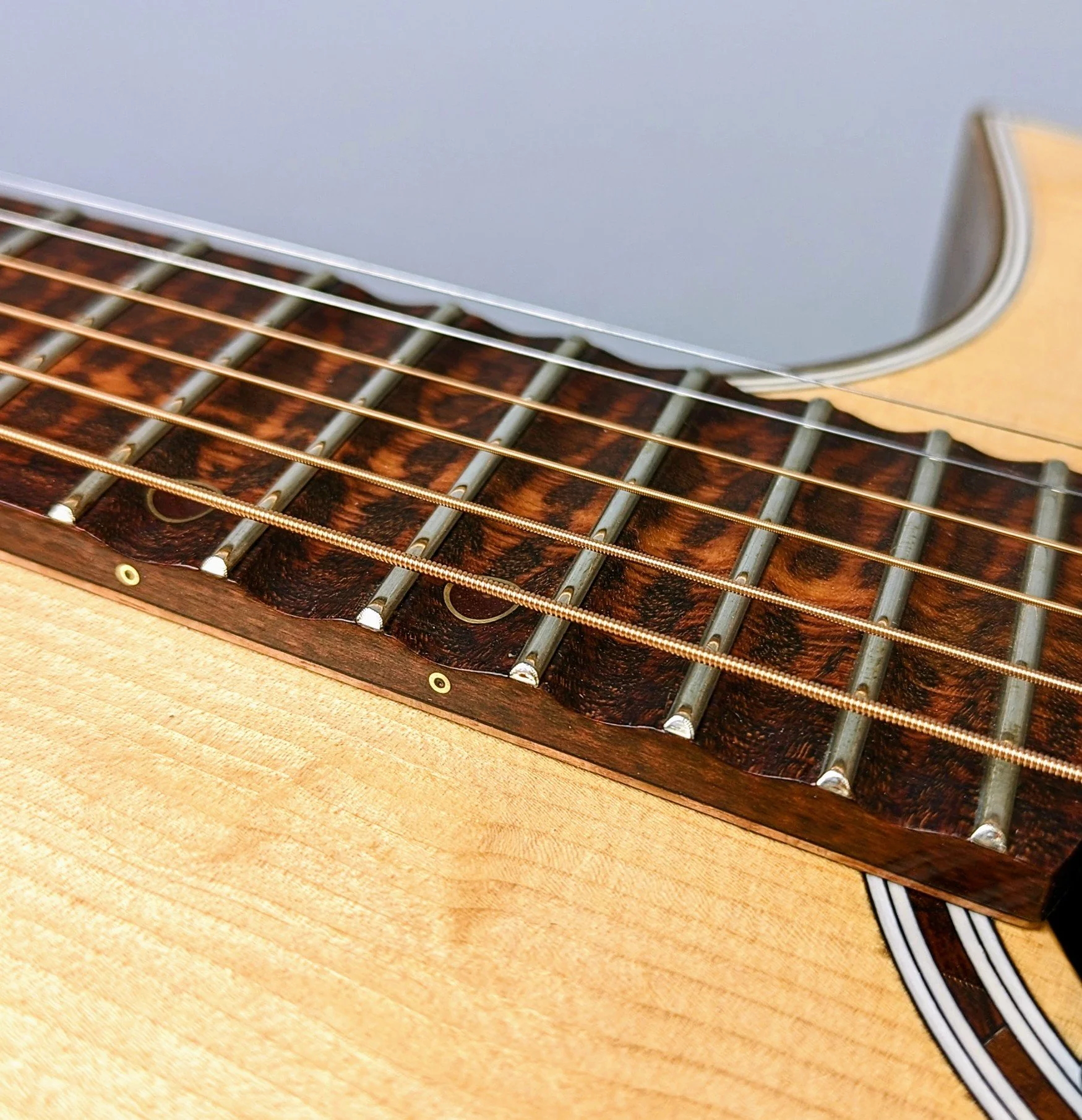 Close-up of a Morgan Kelsey acoustic guitar's fretboard, strings, and body.