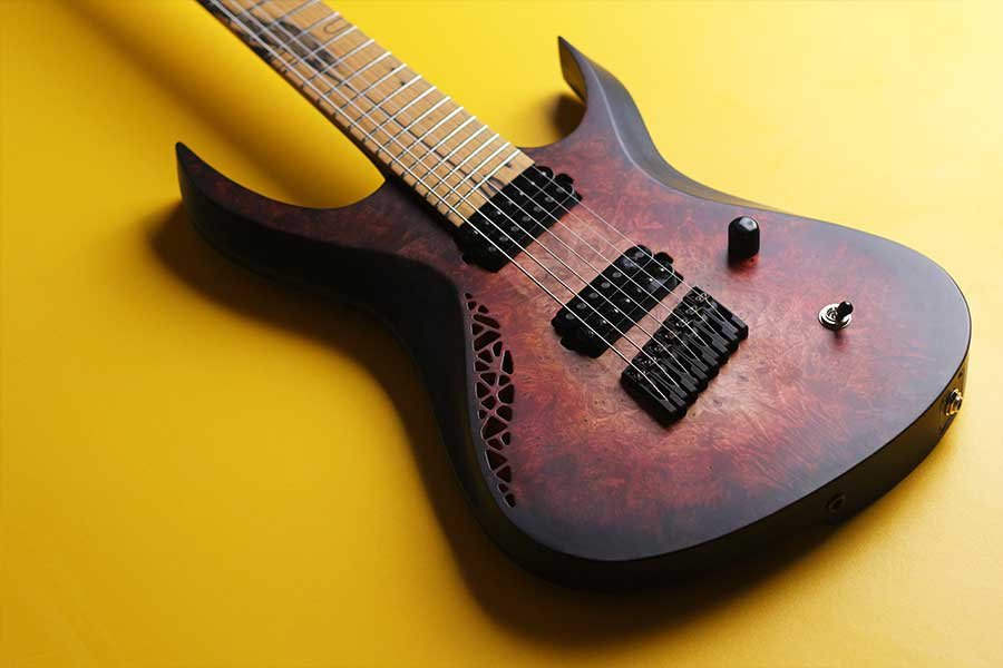 OD Guitars electric with a dark, marbled red and black finish and a natural wood neck, resting on a yellow background.