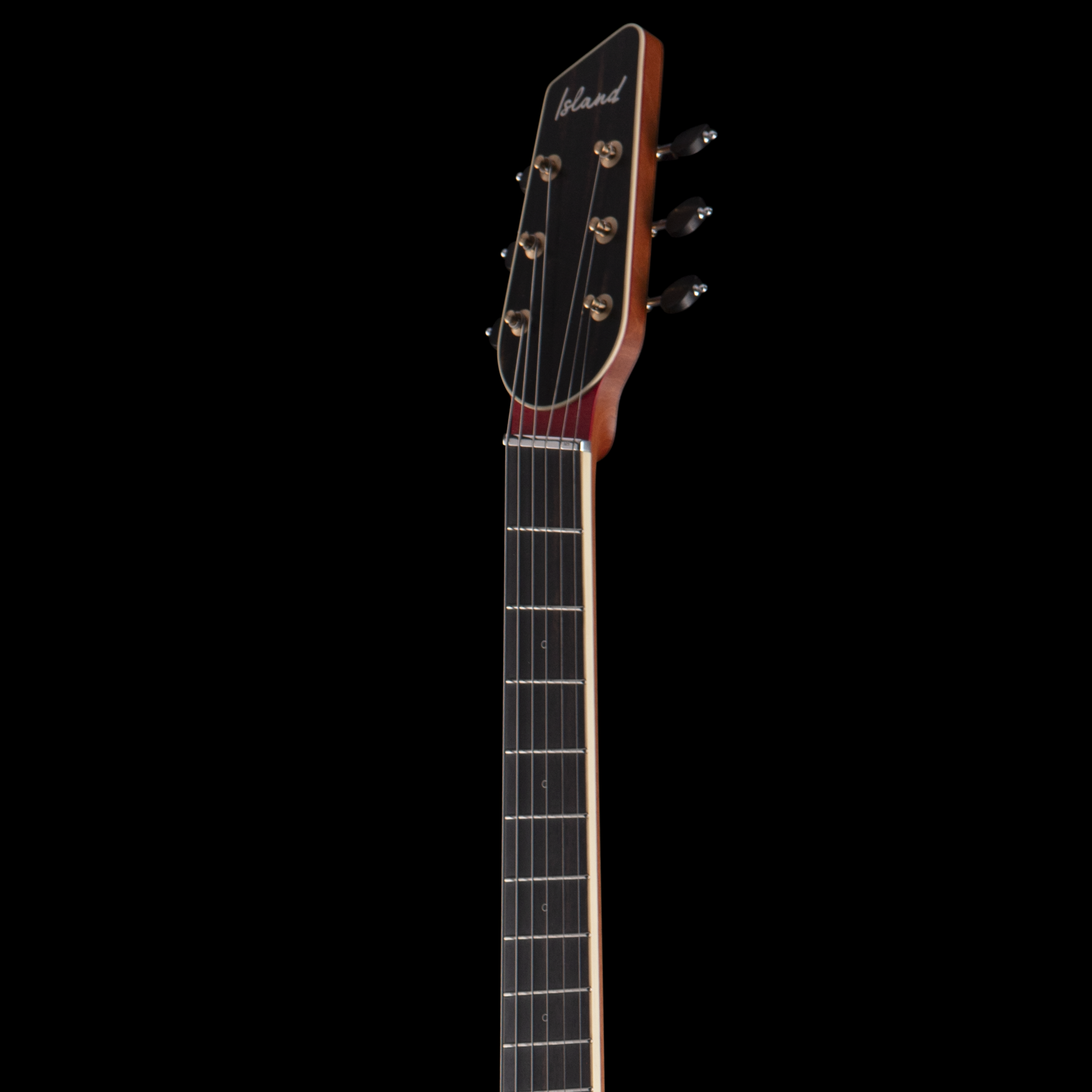 Close-up of an Island Instrument guitar headstock with tuning pegs, strings, and the word 'Island' written on the headstock, against a black background.