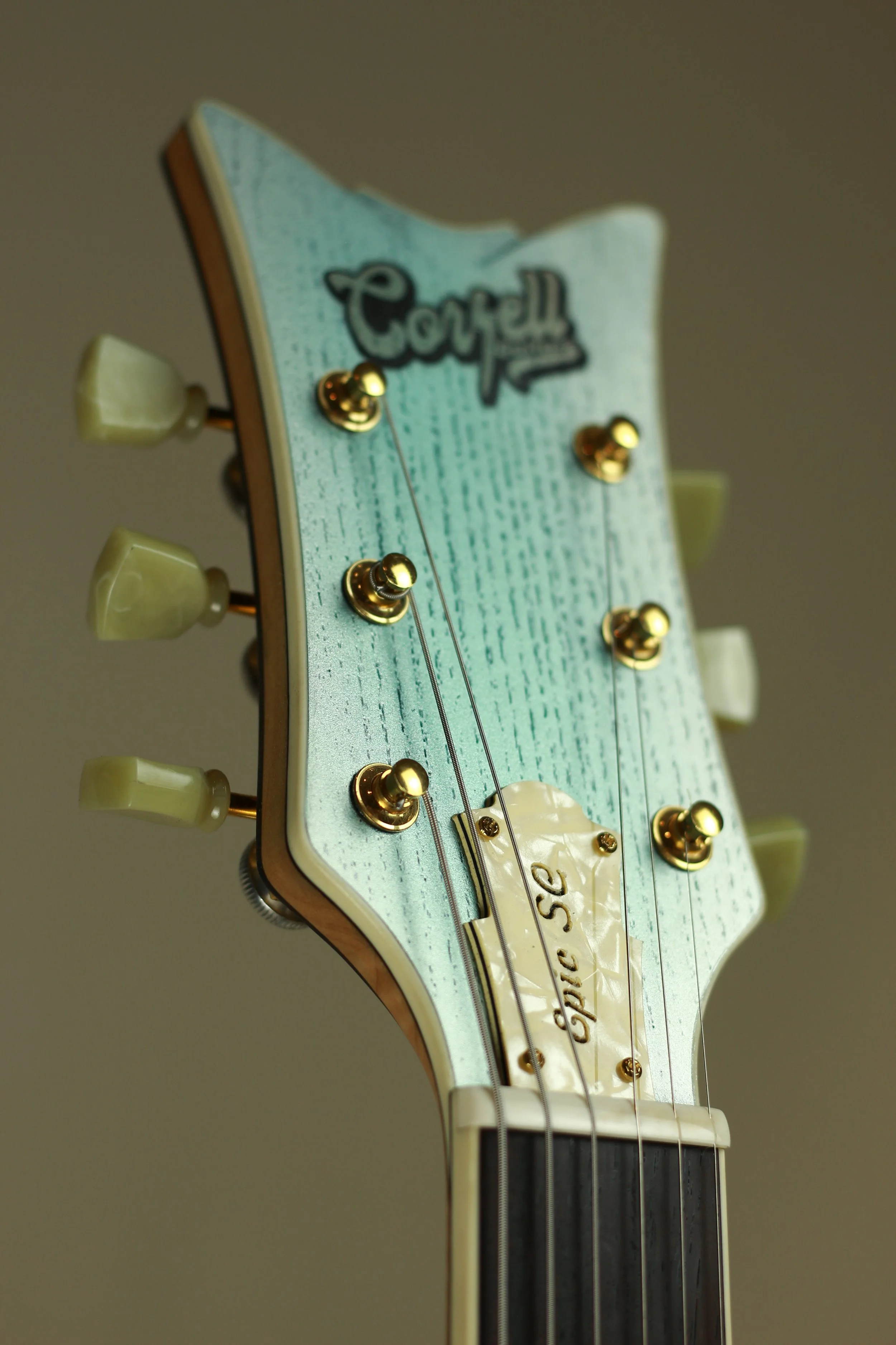 Close-up of the headstock of a vintage Corsell electric guitar, featuring gold tuning pegs and a light green and wood finish.