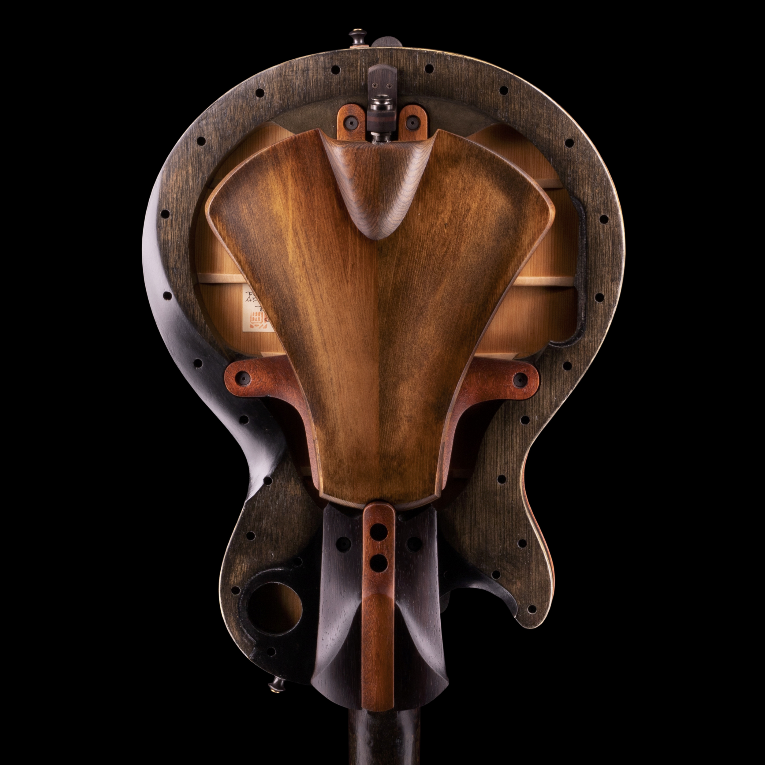 Close-up of the back of a Matusda electric guitar with traditional Japanese craftsmanship, showing its wooden body, strings, and tuning pegs, set against a black background.