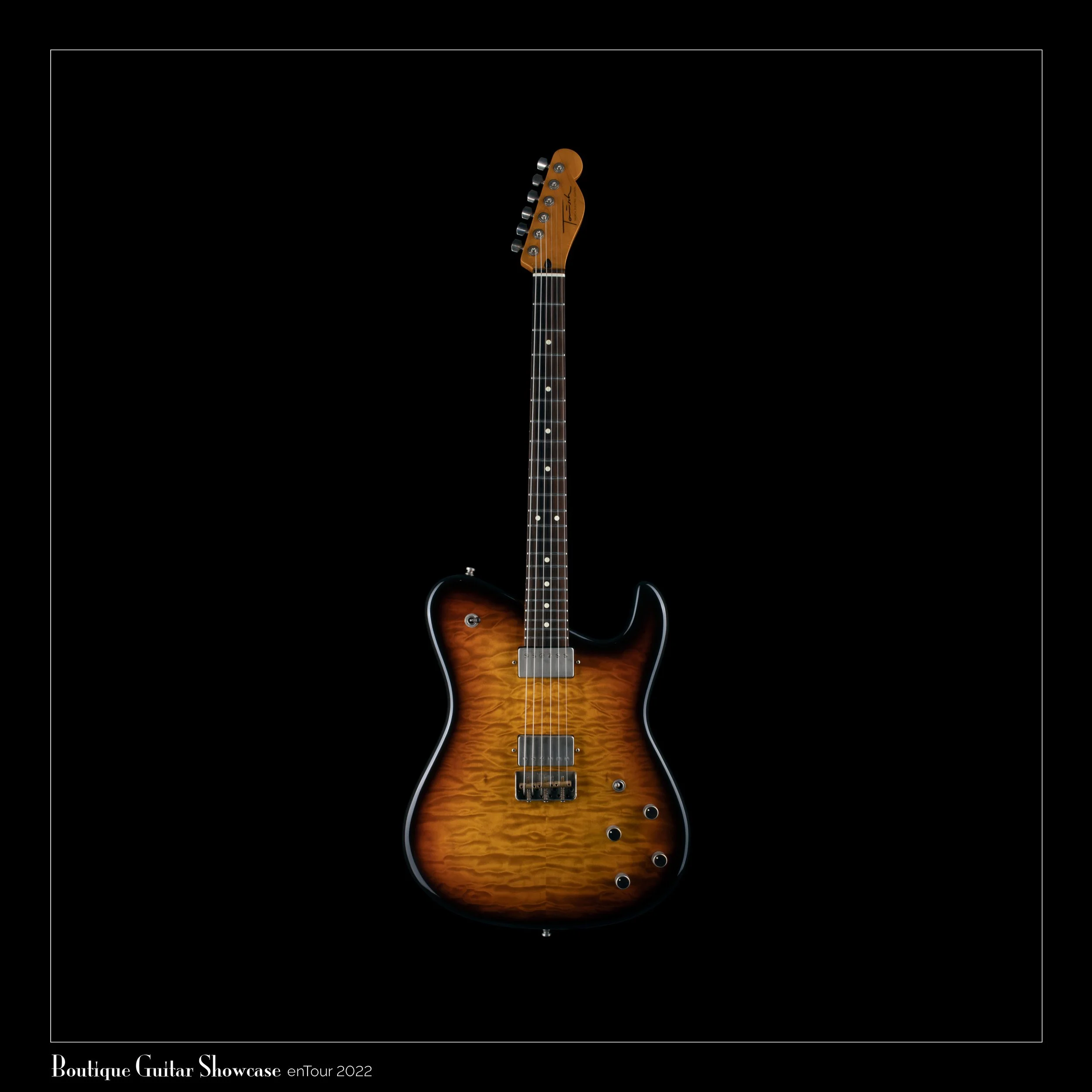A sunburst Tausch electric guitar with a quilted maple top, mounted on a black background, was displayed at a boutique guitar showcase.