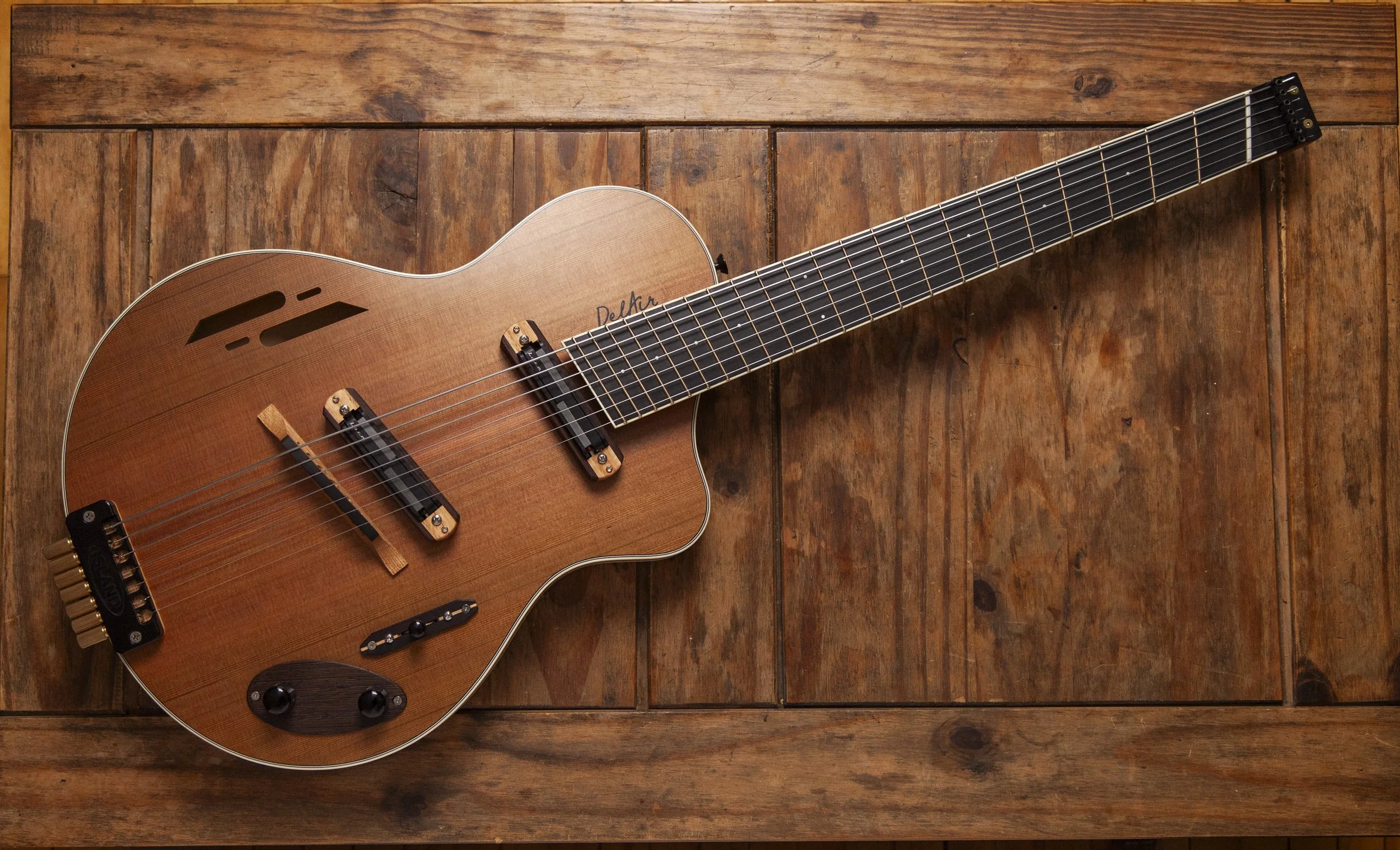 A wooden acoustic Island Instruments guitar lying on a wooden surface.