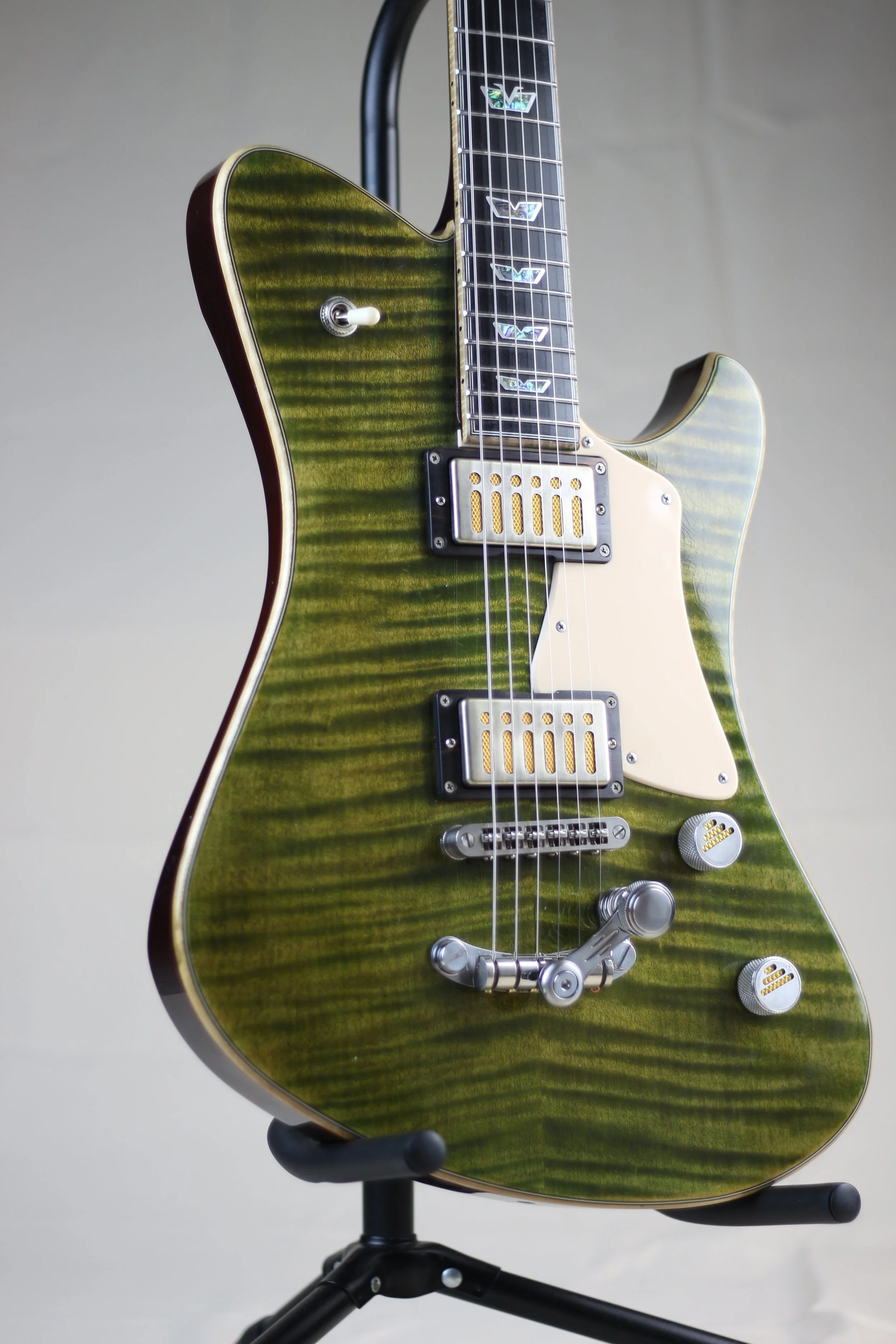 A green electric Corsell guitar with a quilted maple top, white pickguard, and dual humbucker pickups, displayed on a black stand against a plain background.