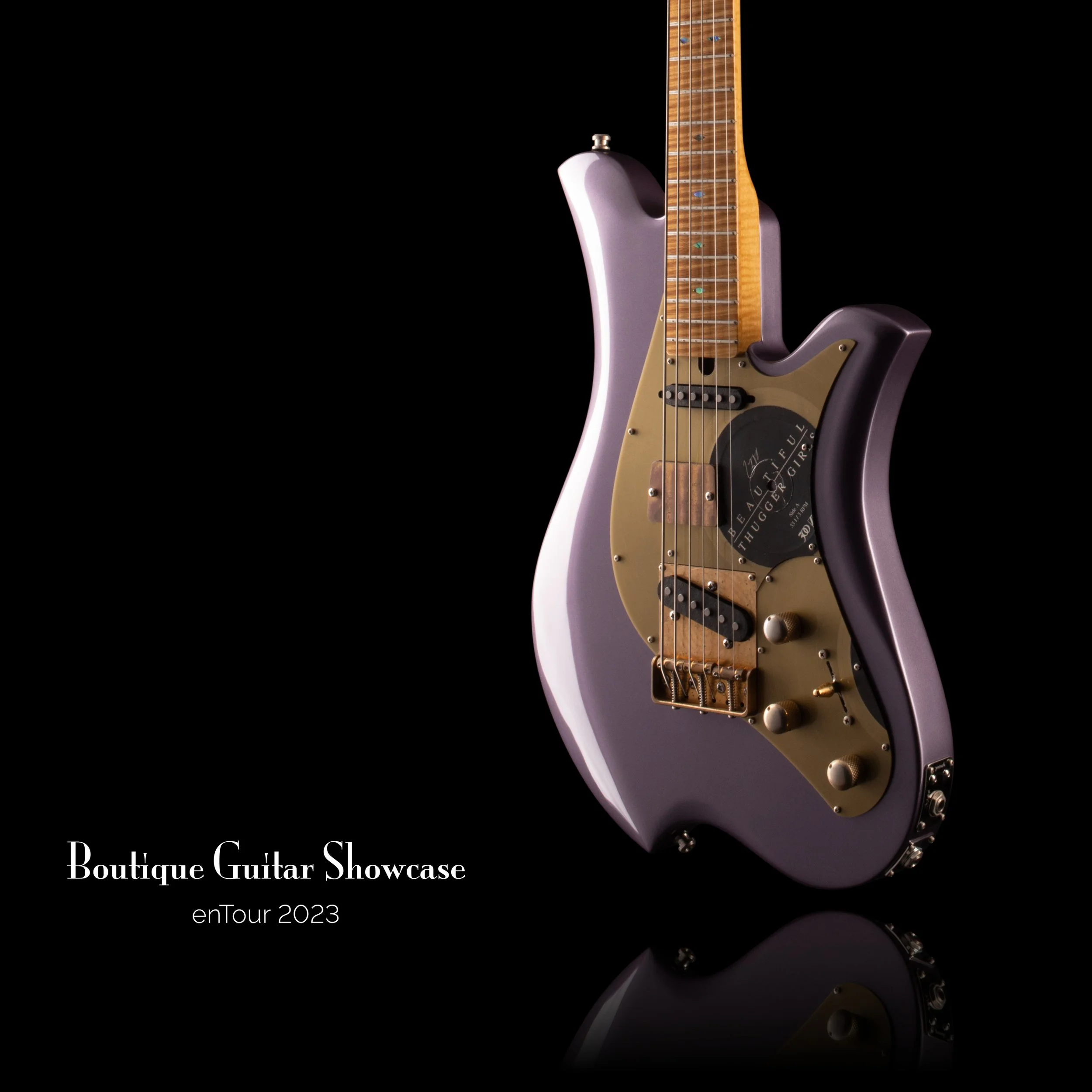 Bacci Baritone electric guitar with a lavender body and metallic gold pickguard on a black background. The text reads 'Boutique Guitar Showcase enTour 2023.'