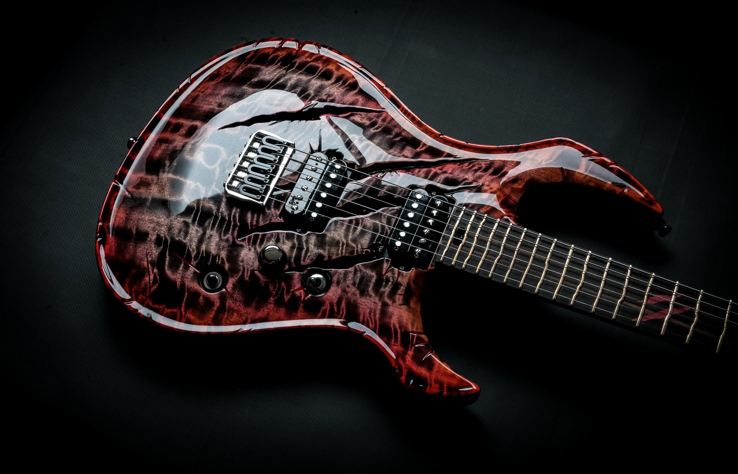A red and black GNG Giulio Negrini electric guitar with a cracked skull design on the body, set against a black background.