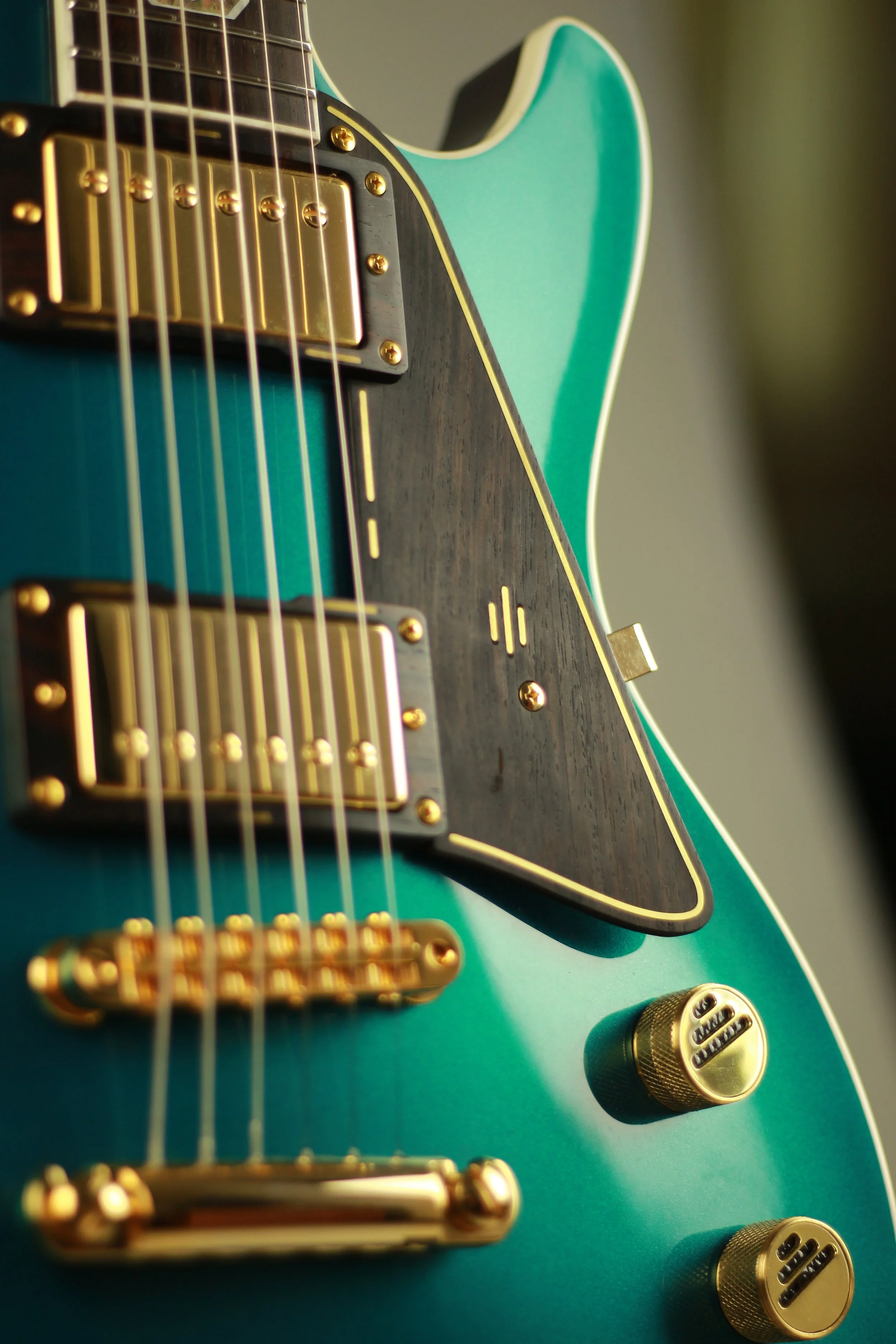 Close-up of a Corsell electric guitar with a teal body, gold hardware, and a black and dark wood pickguard.