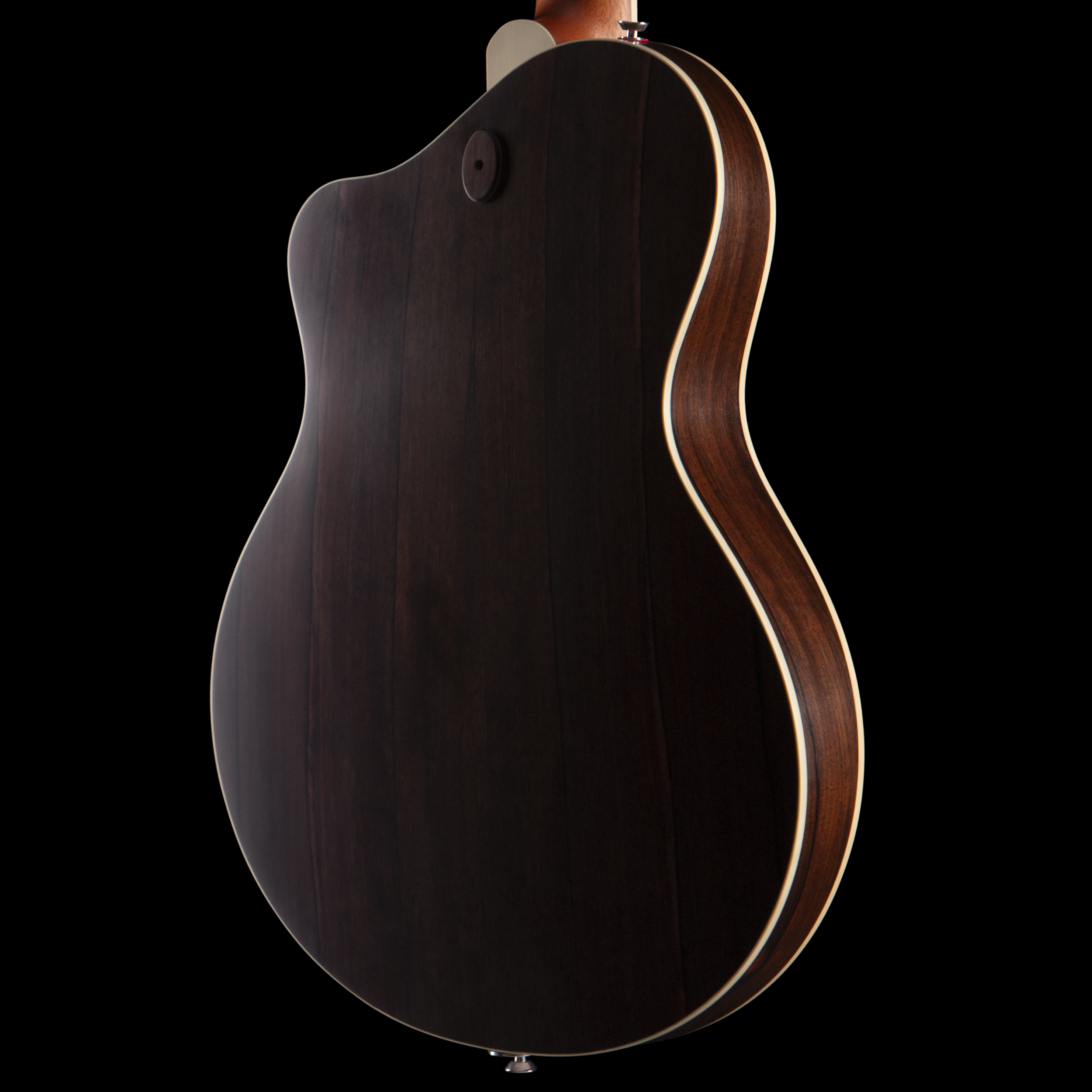 Back of a wooden acoustic Island Instrument guitar with a dark finish and white binding, isolated on black background.